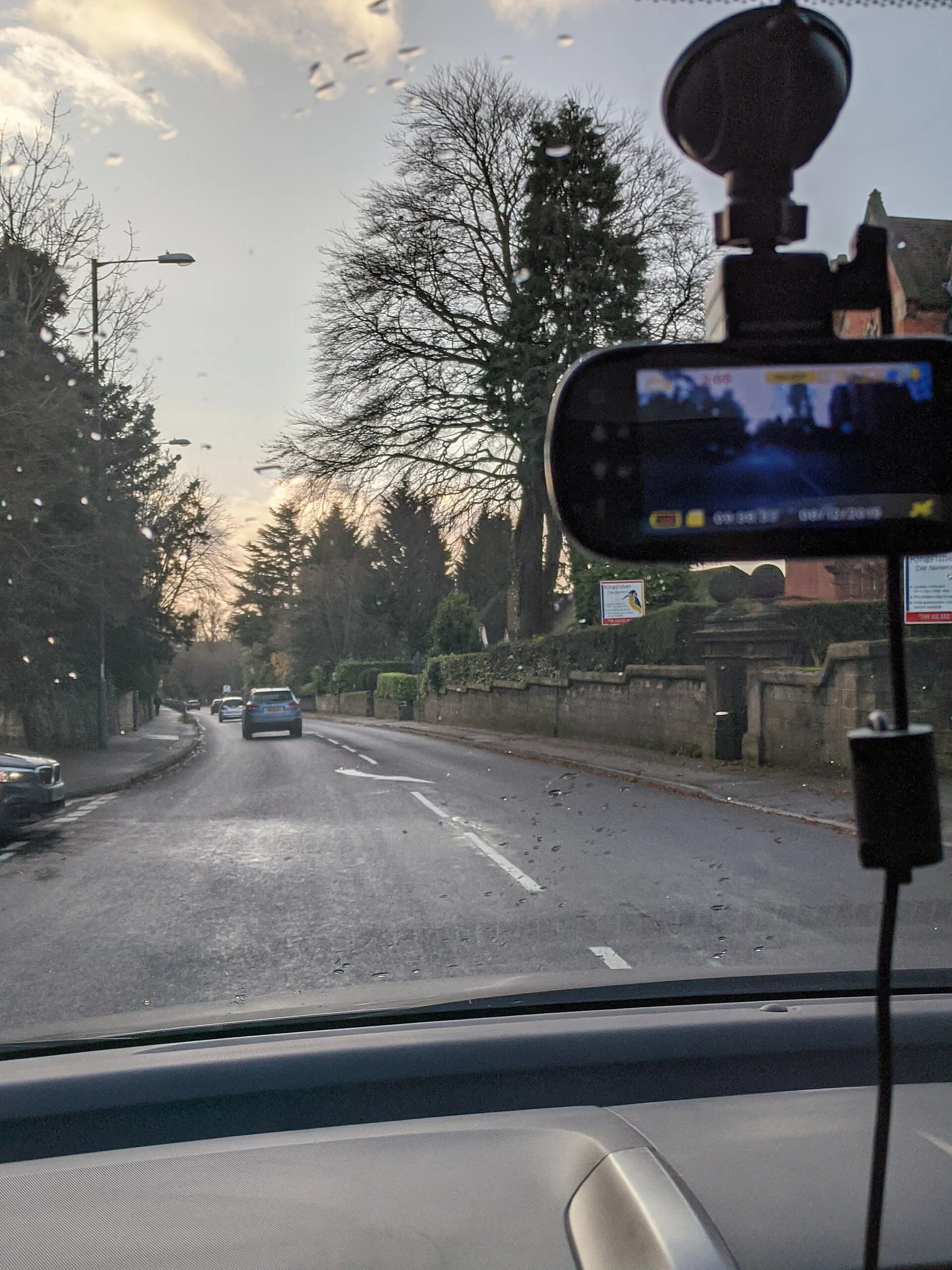 A dash cam mounted behind the rear-view mirror, recording the road ahead