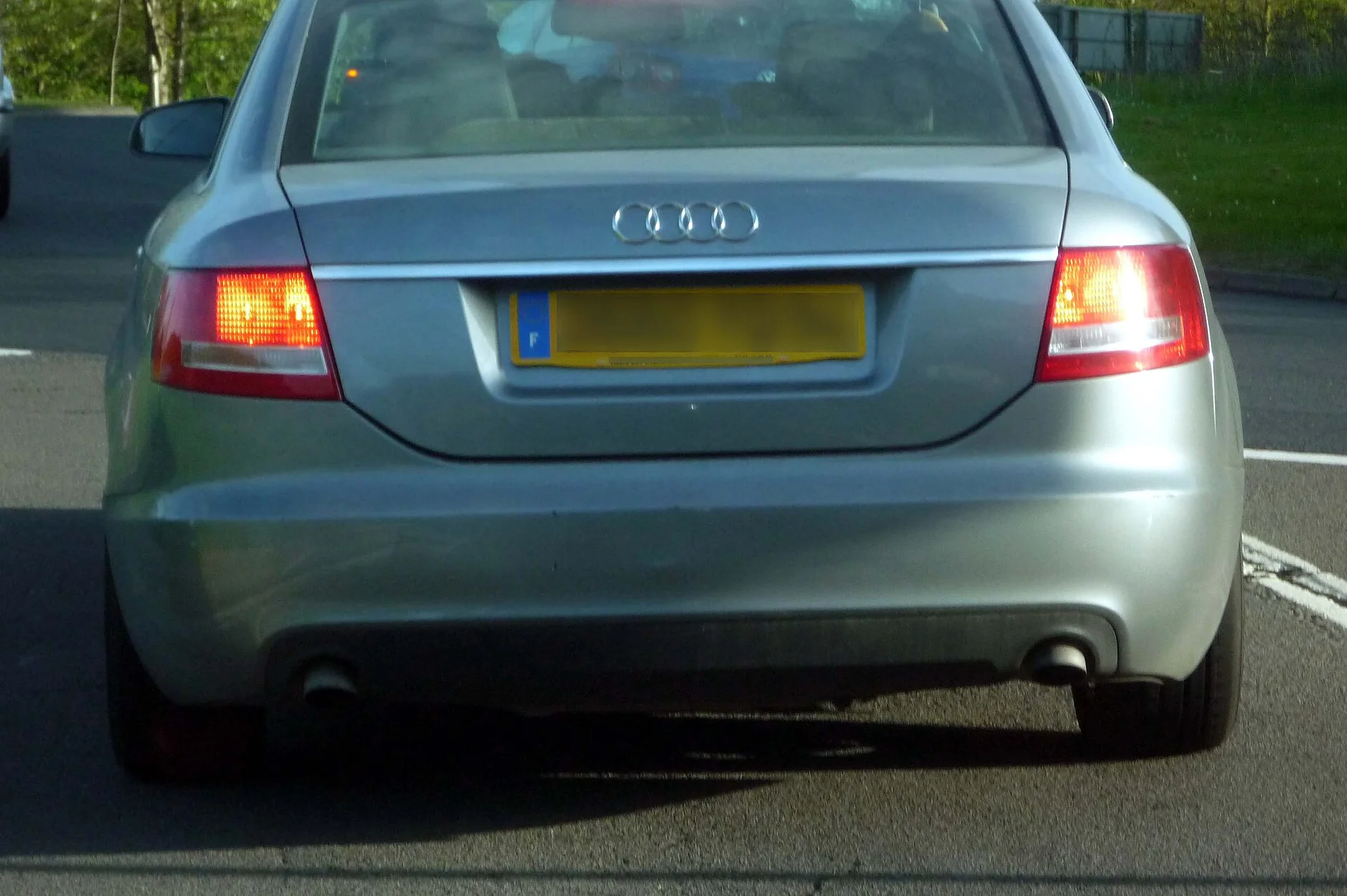 The rear of a car showing its exhaust tailpipe, the vehicle exhaust that is the carbon monoxide source this guide warns about when sleeping in a car with the engine running.