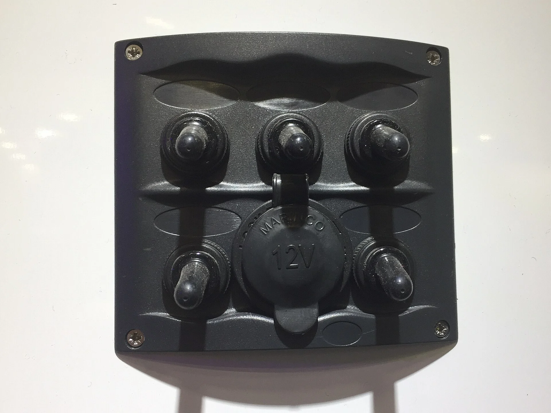A black switch panel fitted with a round 12-volt power socket and rocker switches.
