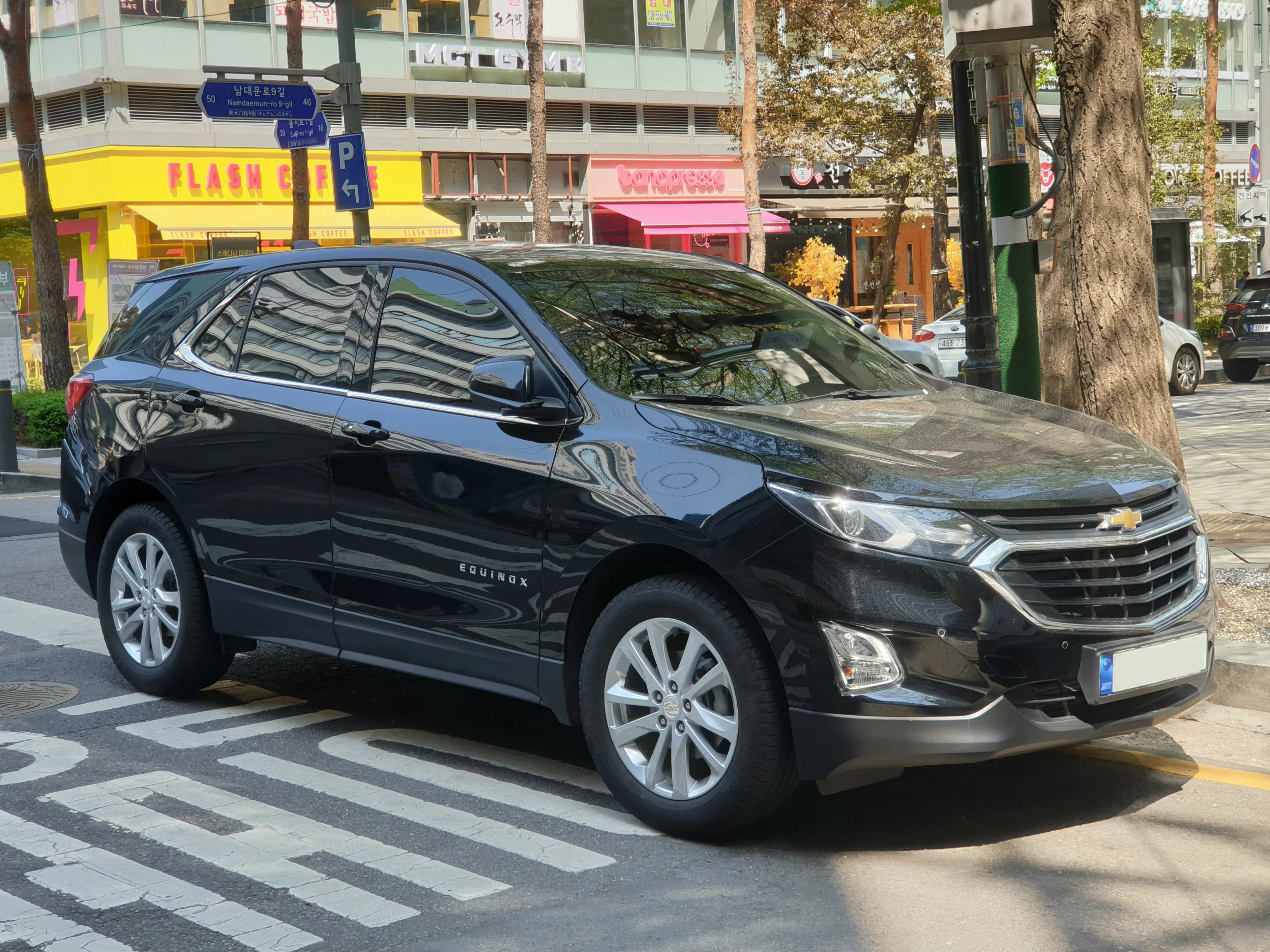Black Chevrolet Equinox LT compact SUV, third-generation, front three-quarter view with a split chrome grille, parked on a city street.