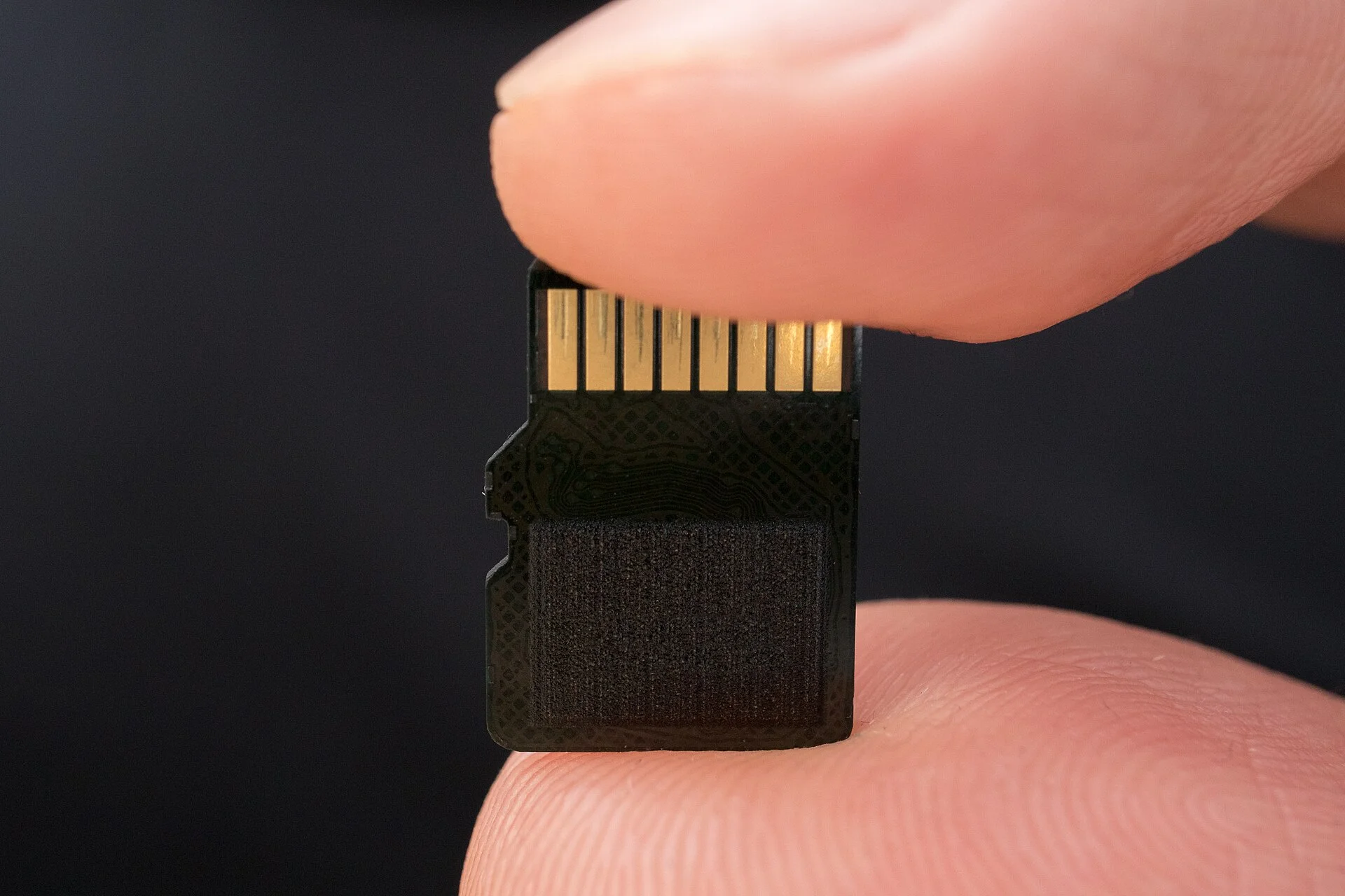 A microSD card held between two fingers, the tiny SD card a dashcam records footage onto