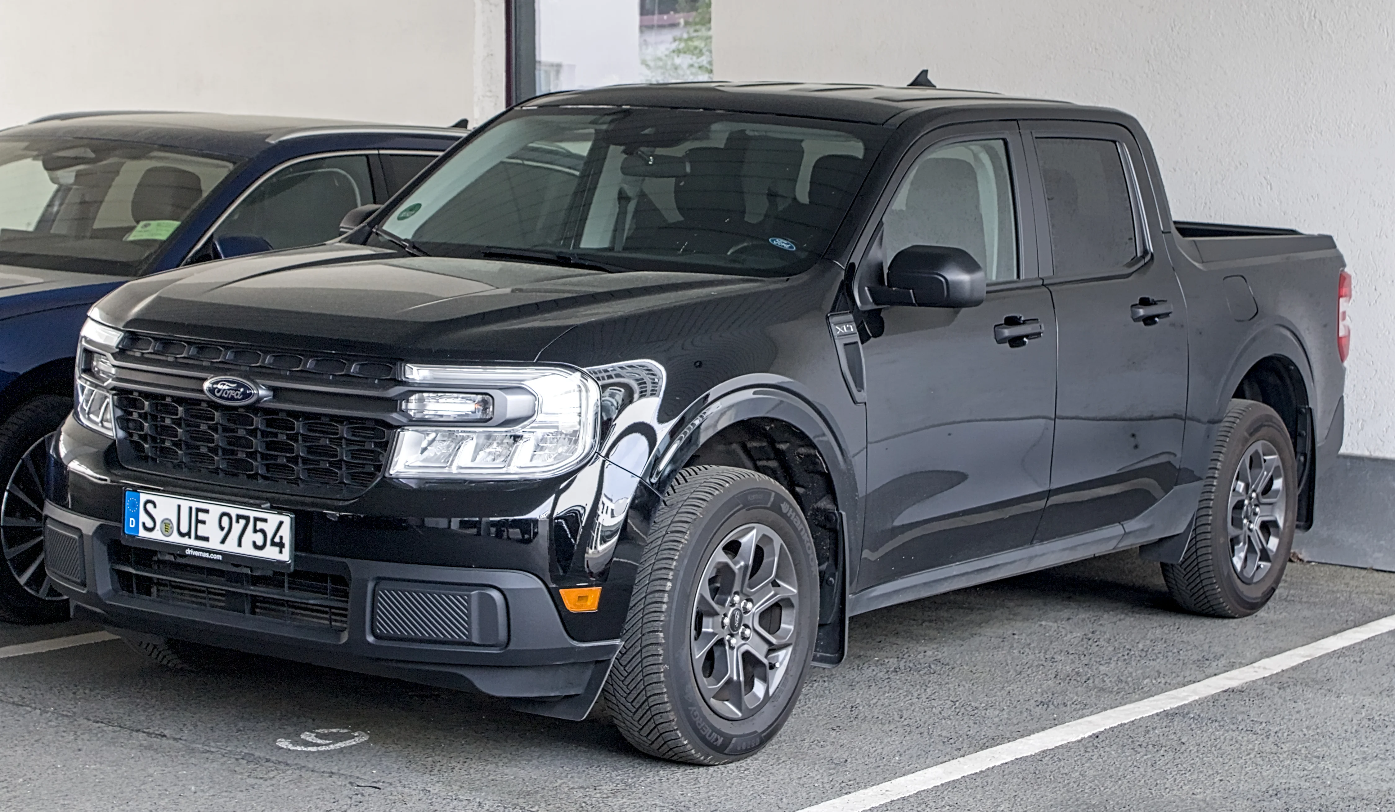 Black Ford Maverick compact pickup truck, current generation, front three-quarter view parked at a kerb.