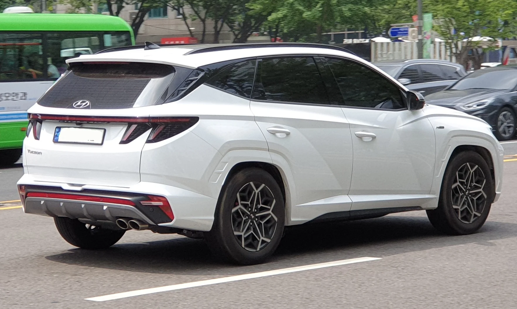 White Hyundai Tucson N Line SUV, current NX4 generation, rear three-quarter view on a city street.