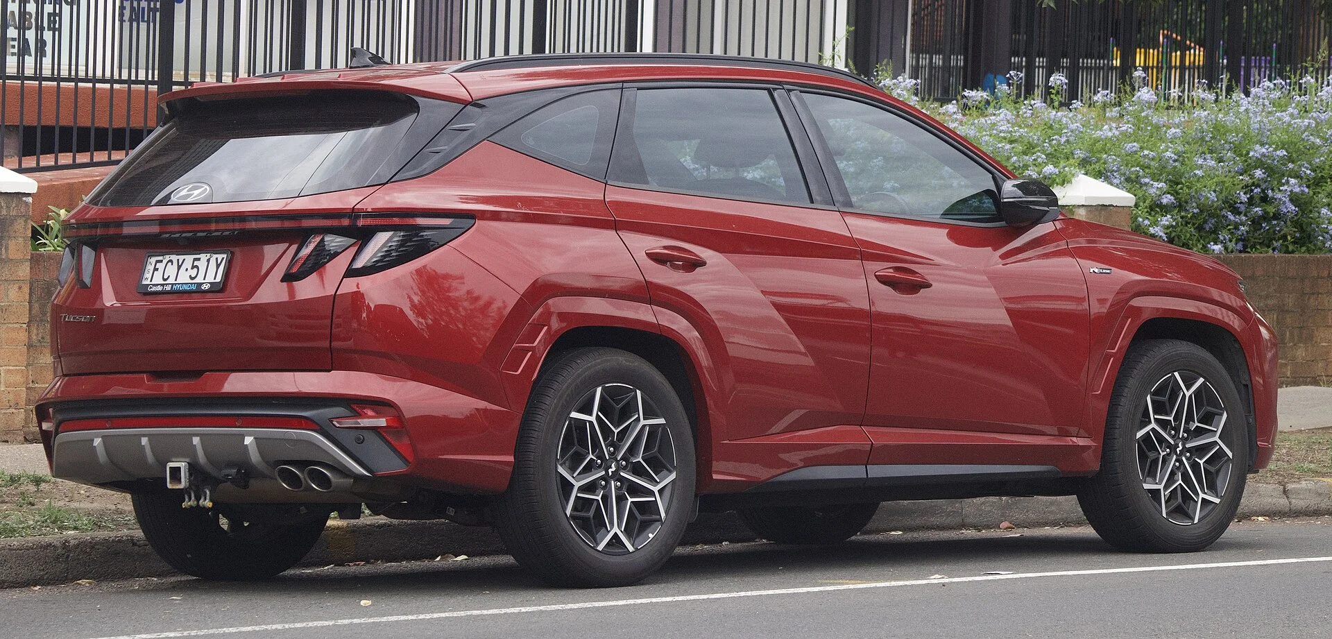 A Hyundai Tucson (NX4) in red, rear three-quarter showing the liftgate you load a sleep setup through