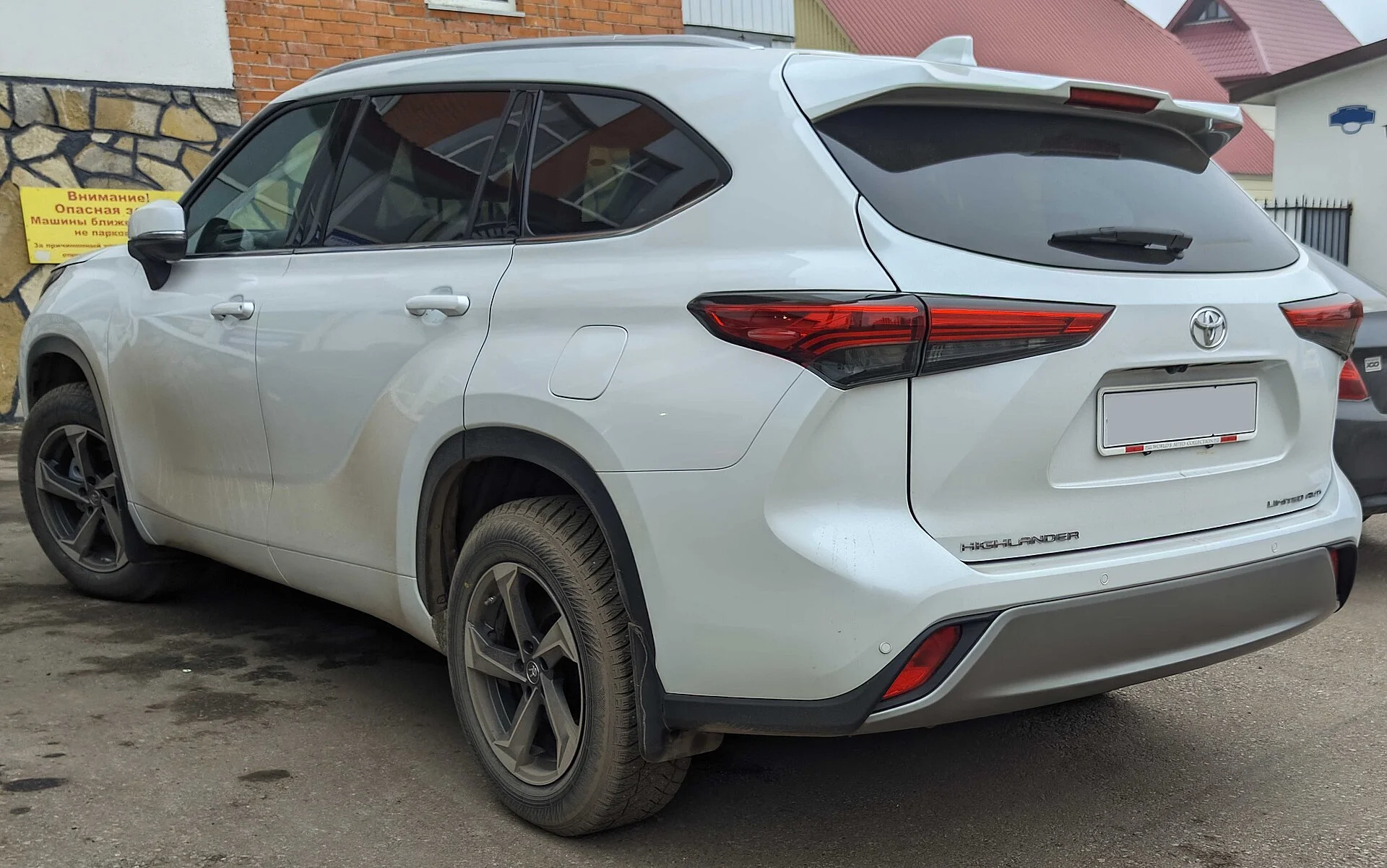 White Toyota Highlander Limited SUV, rear three-quarter view showing the HIGHLANDER tailgate badge and Toyota logo