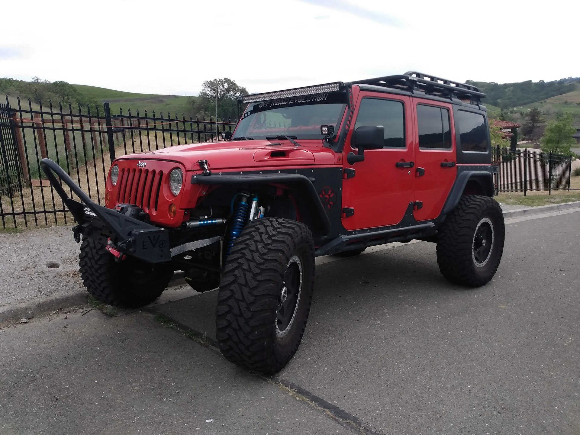 Red lifted Jeep Wrangler Rubicon with oversized off-road tires, front three-quarter view