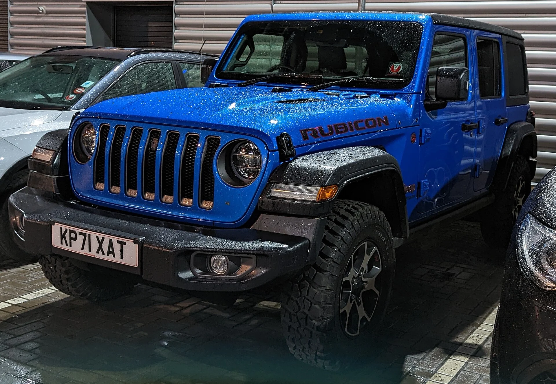 Blue Jeep Wrangler Rubicon parked, front view showing the grille and approach angle
