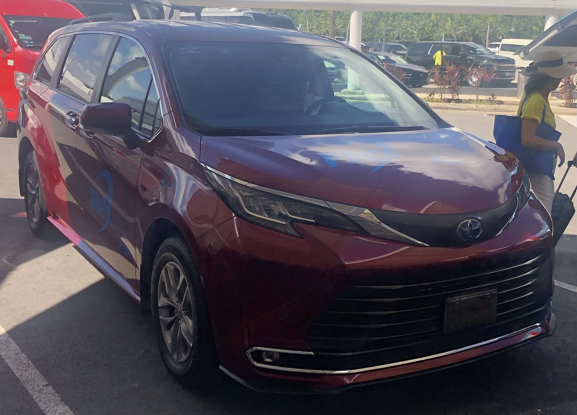 Dark-red Toyota Sienna minivan, current fourth-generation XL40 carrying a car-share service wrap, front three-quarter view.