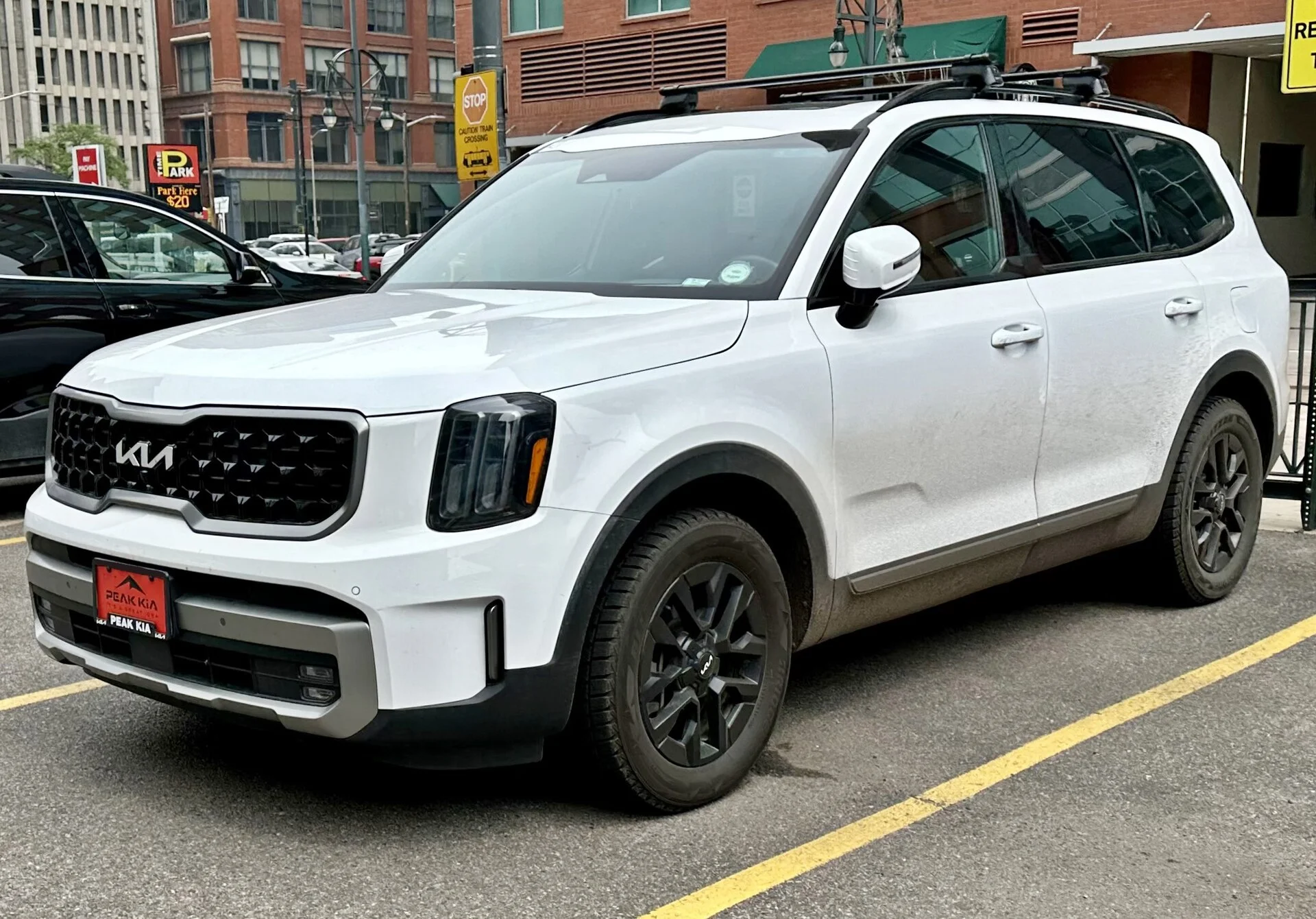 Kia Telluride — a white Telluride, front and side three-quarter view showing the roof rails an awning mounts to