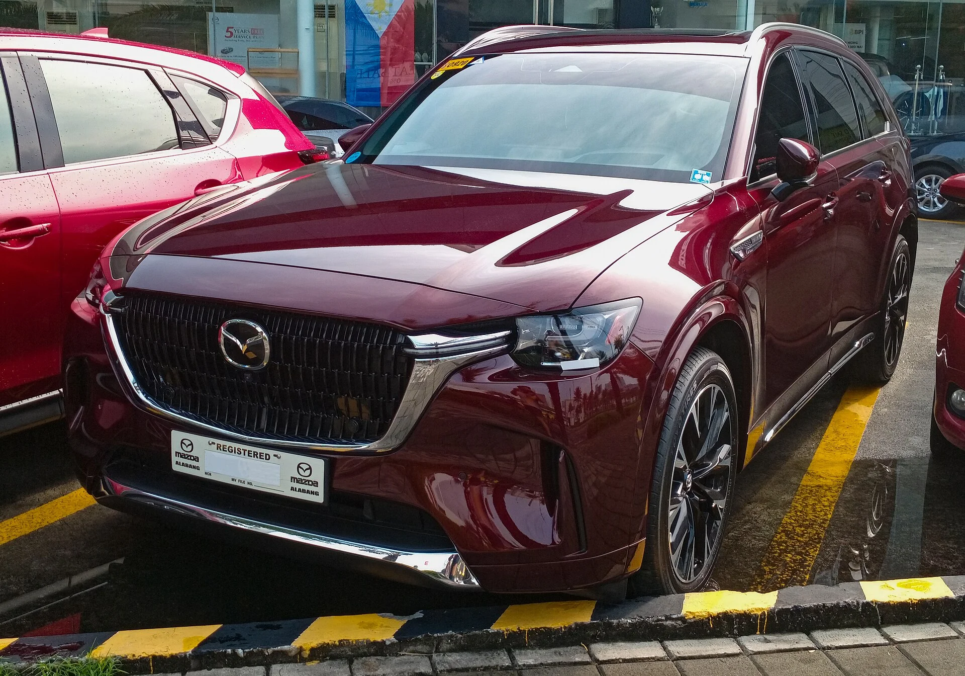Mazda CX-90 (2024) in dark red, front three-quarter view