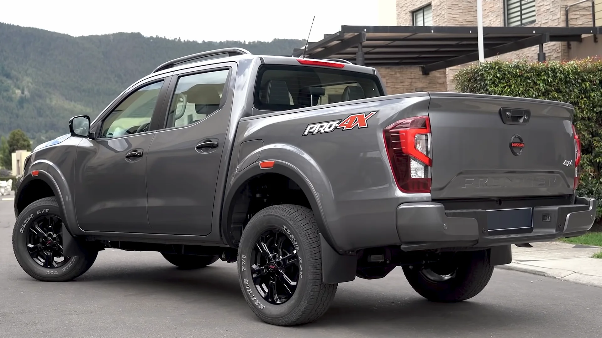 Grey Nissan Frontier Pro-4X crew-cab pickup, rear three-quarter view showing its cargo bed, PRO-4X decal, tailgate, and black alloy wheels