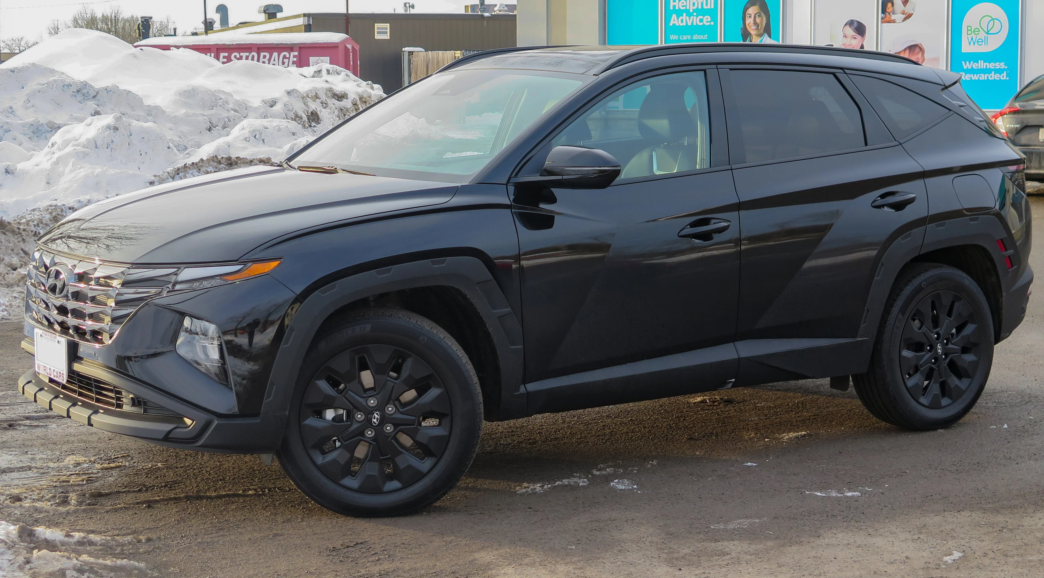 Black Hyundai Tucson compact SUV, current NX4 generation, front three-quarter view in a winter dealership lot.