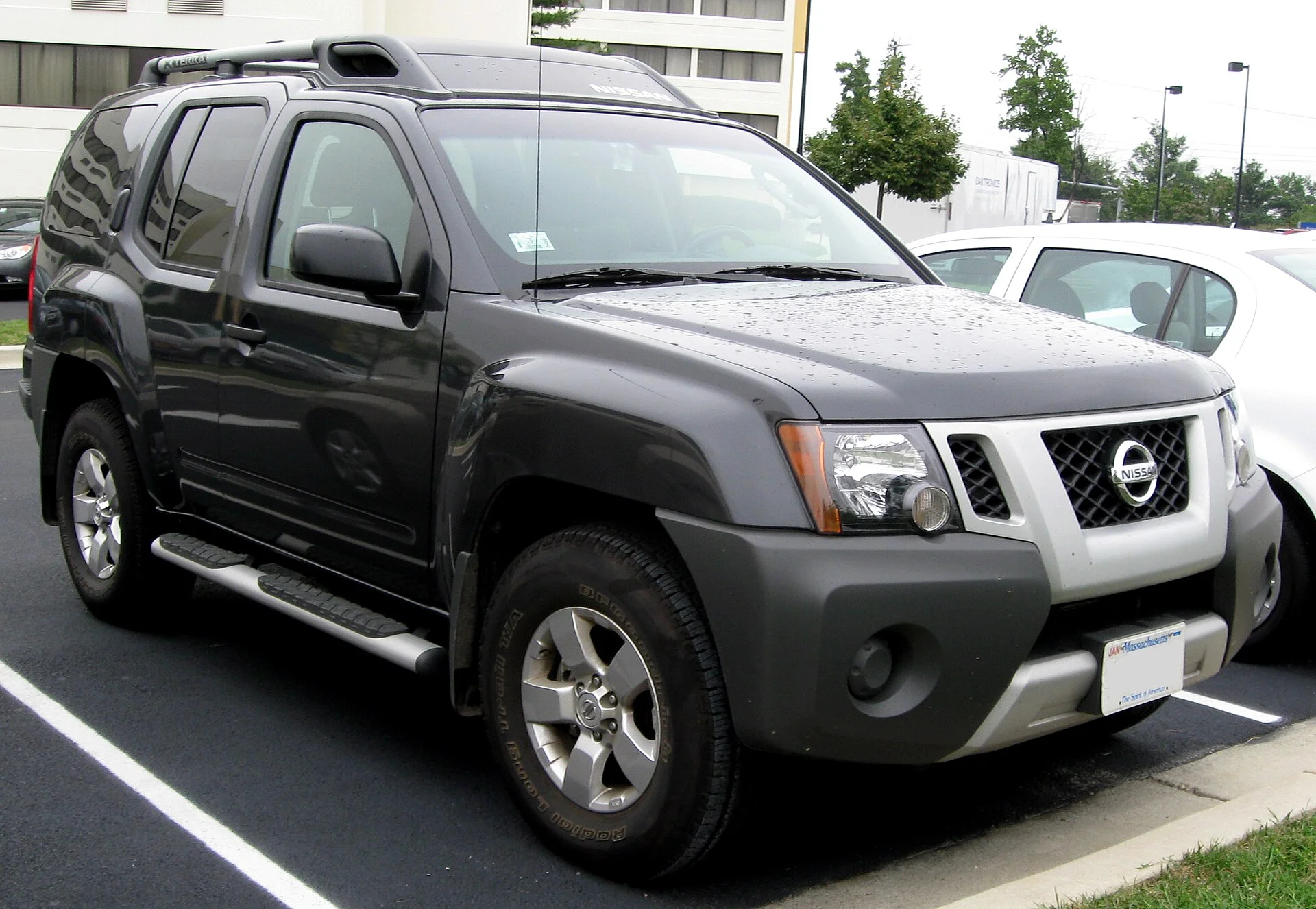 Dark grey second-generation Nissan Xterra SUV with a roof basket, front three-quarter view showing the Nissan grille badge