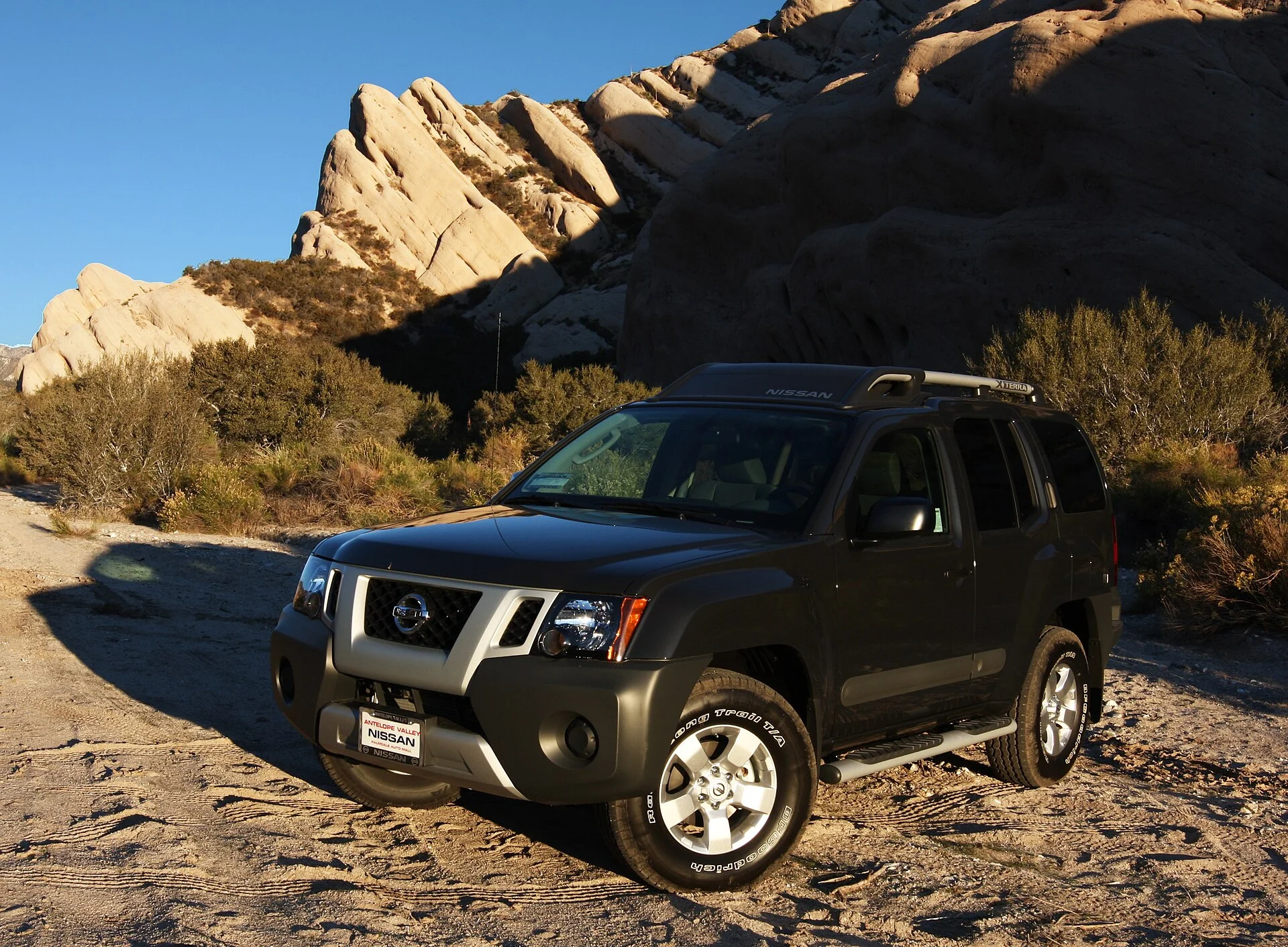 Nissan Xterra — a dark-grey 2011 Xterra on a rocky trail, front three-quarter view showing its off-road ground clearance