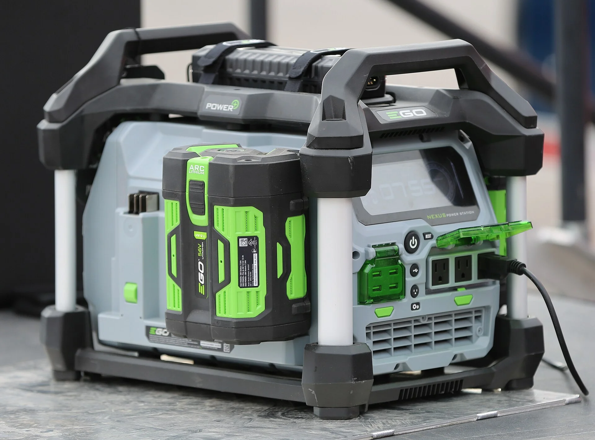 Grey and black EGO Nexus portable power station with a green battery pack fitted, three-quarter view showing its AC outlets and side ventilation