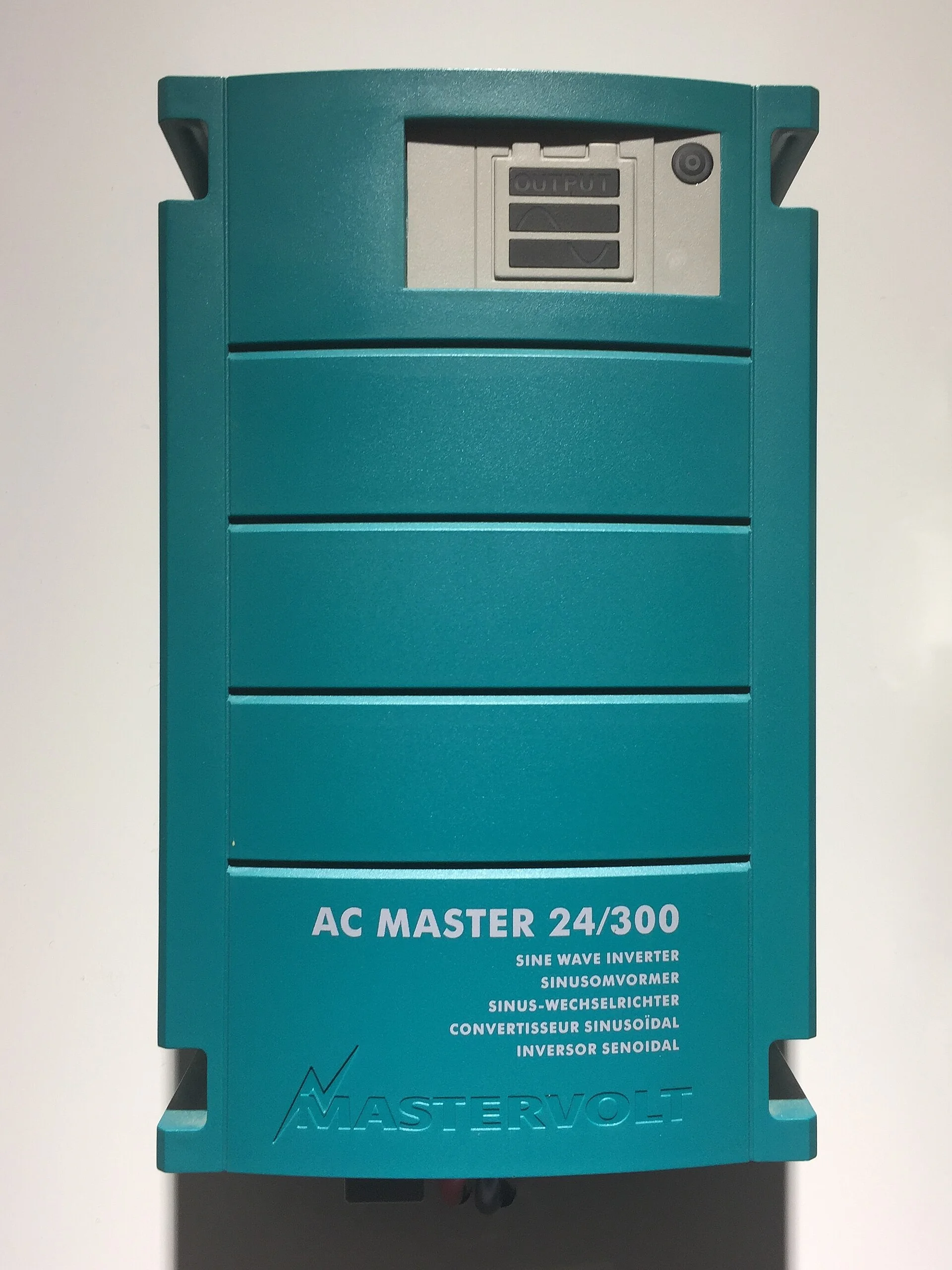 A teal Mastervolt AC Master 24/300 sine-wave power inverter with an output display, mounted on a wall.