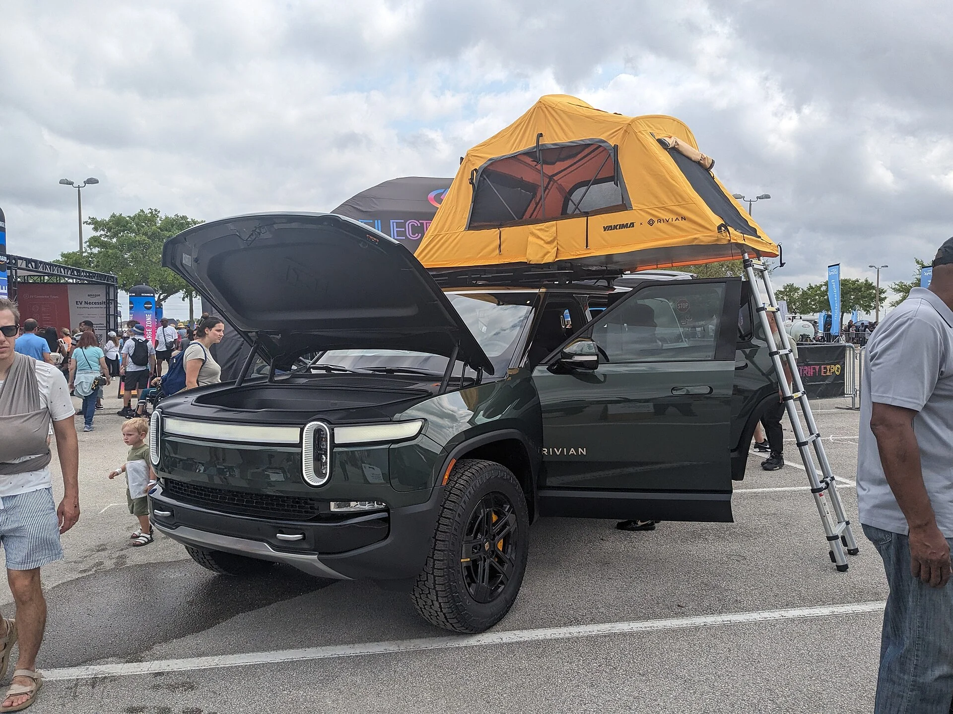 Green Rivian R1S with a rooftop tent set up for camping