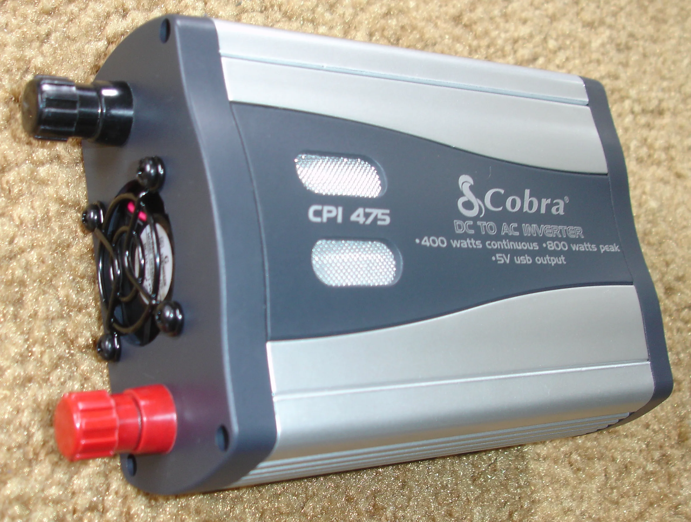 A silver-and-black Cobra CPI-475 400-watt car power inverter with two AC outlets and a USB port, seen from the rear connection panel.