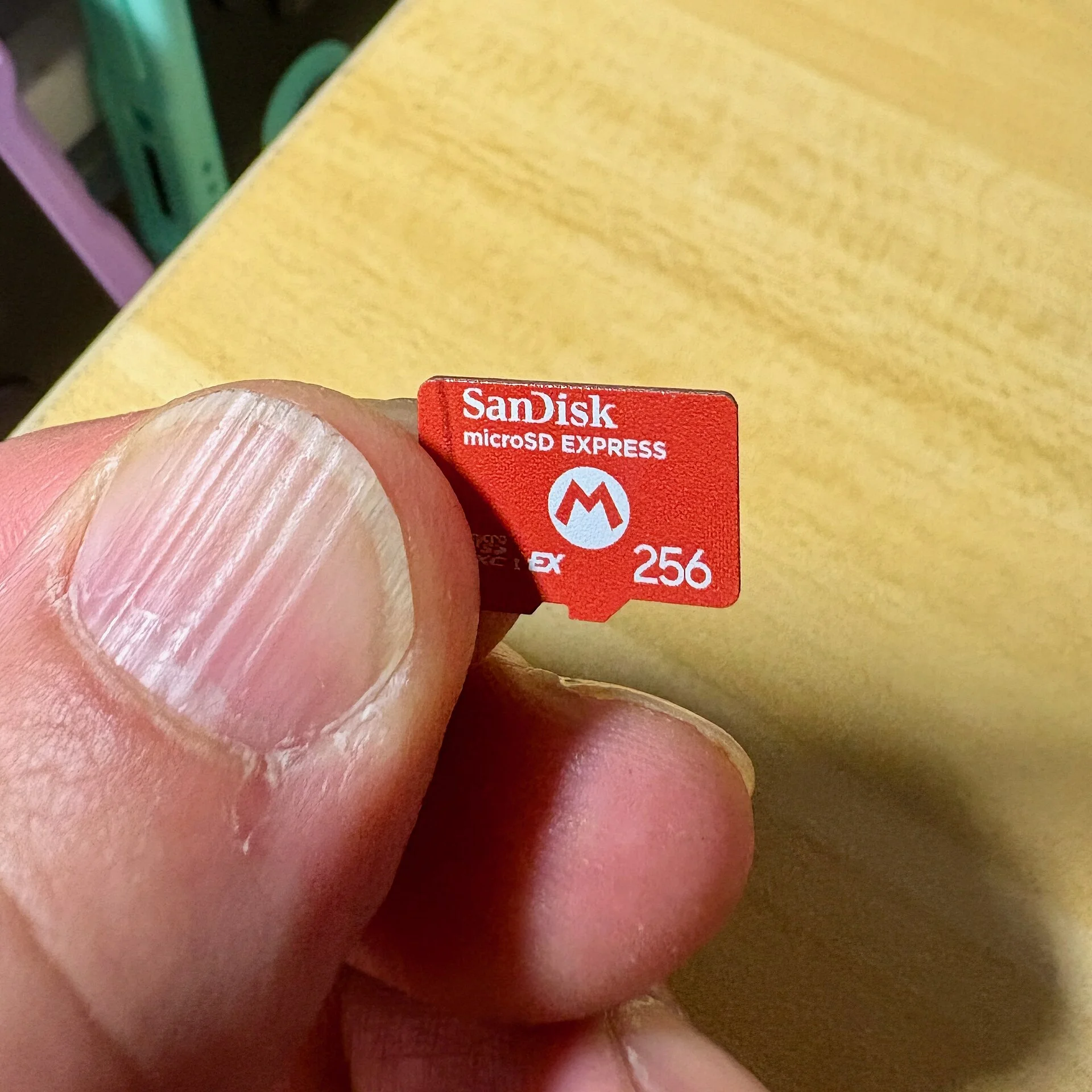 A SanDisk microSD Express card held in hand, showing the compact microSD format
