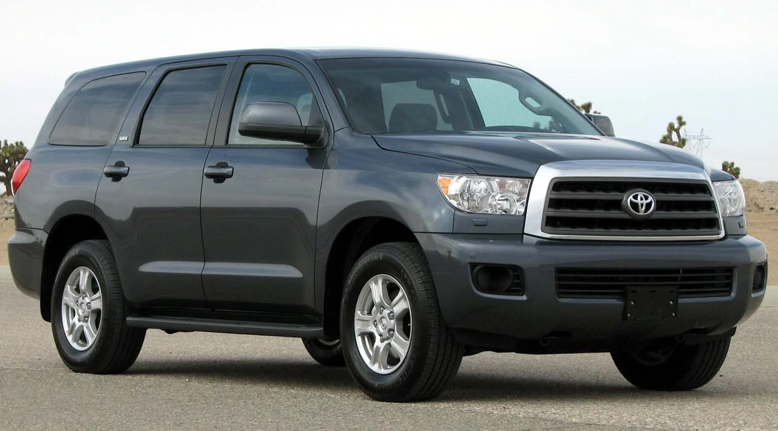 Grey Toyota Sequoia SR5 full-size SUV, front three-quarter view showing the chrome Toyota grille, parked in a desert setting