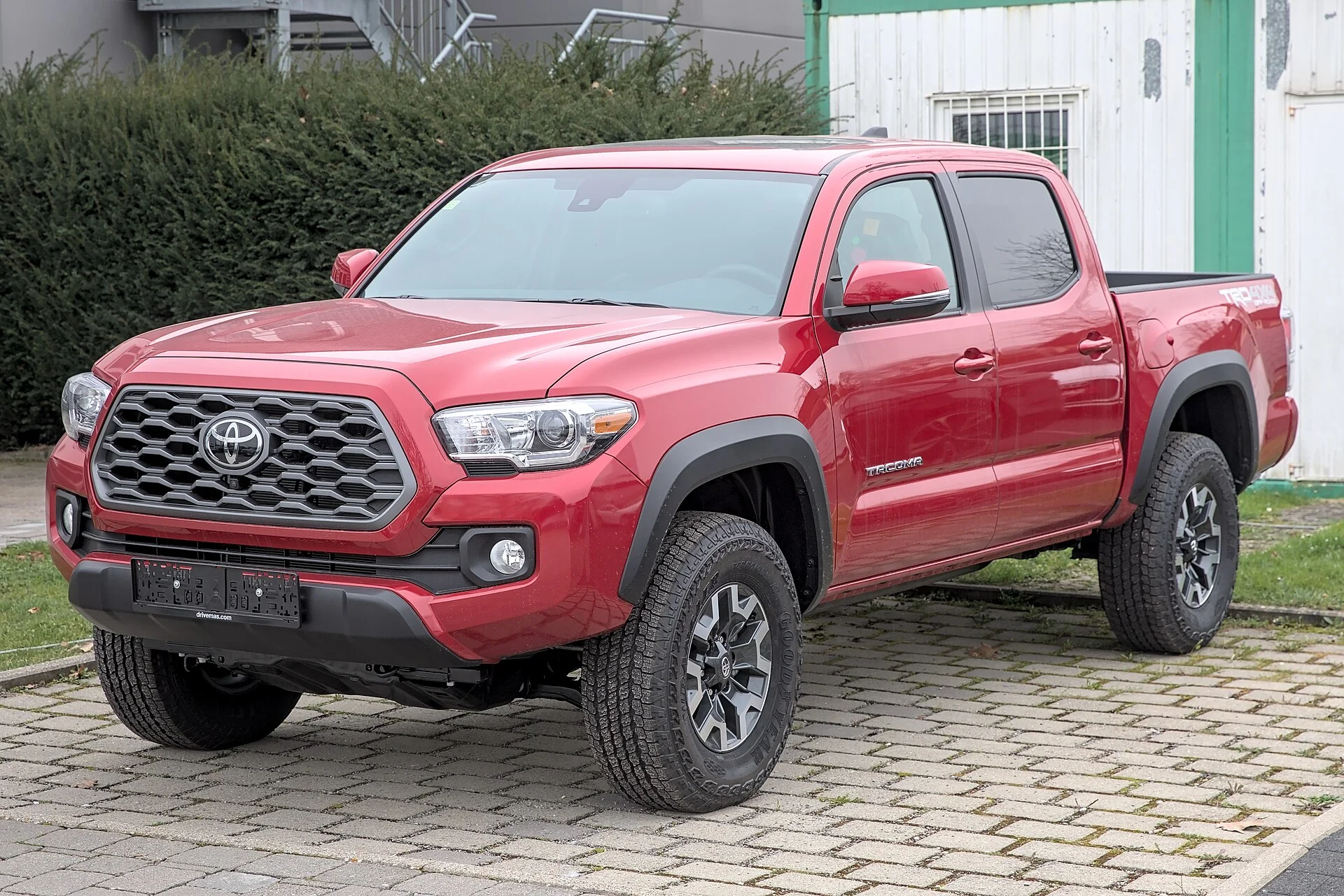 Red Toyota Tacoma (third generation, N300) TRD pickup, front three-quarter view on a road