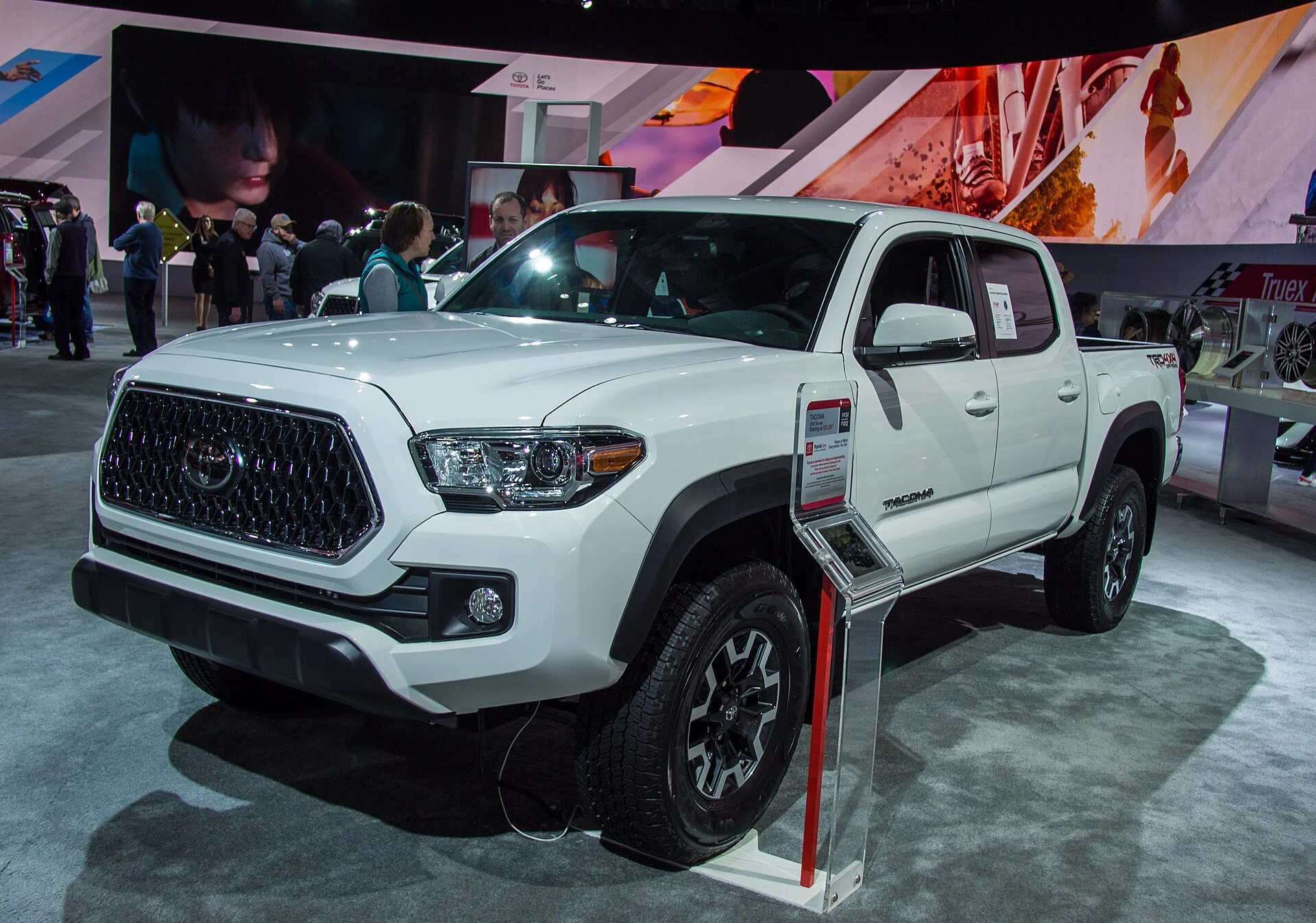 White Toyota Tacoma TRD pickup on an auto-show floor, front side view (2018)