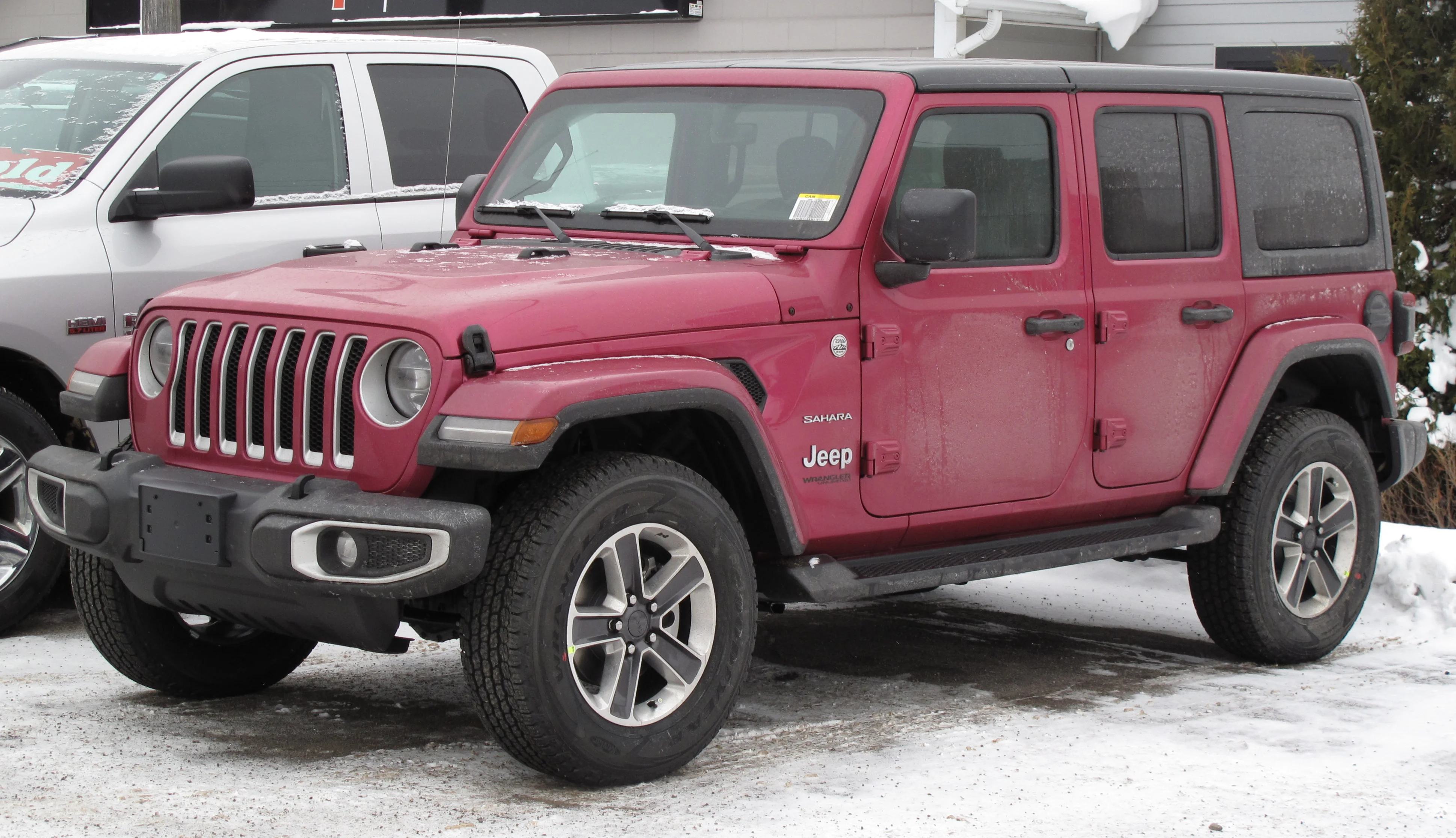 Magenta Tuscadero-Pearl Jeep Wrangler Unlimited Sahara four-door hardtop, current JL generation, front three-quarter view in a snowy dealership lot.