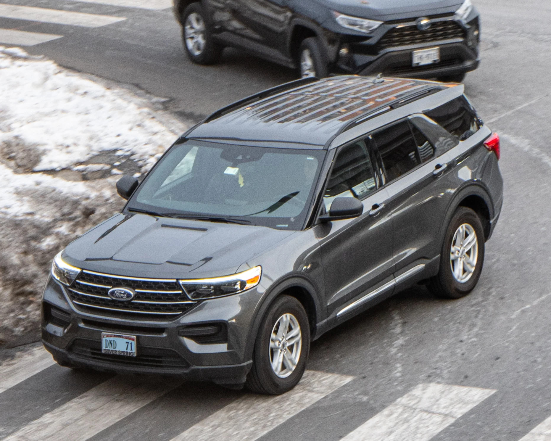 Gray Ford Explorer, current sixth-generation U625, front three-quarter view from a high angle at a US crosswalk.