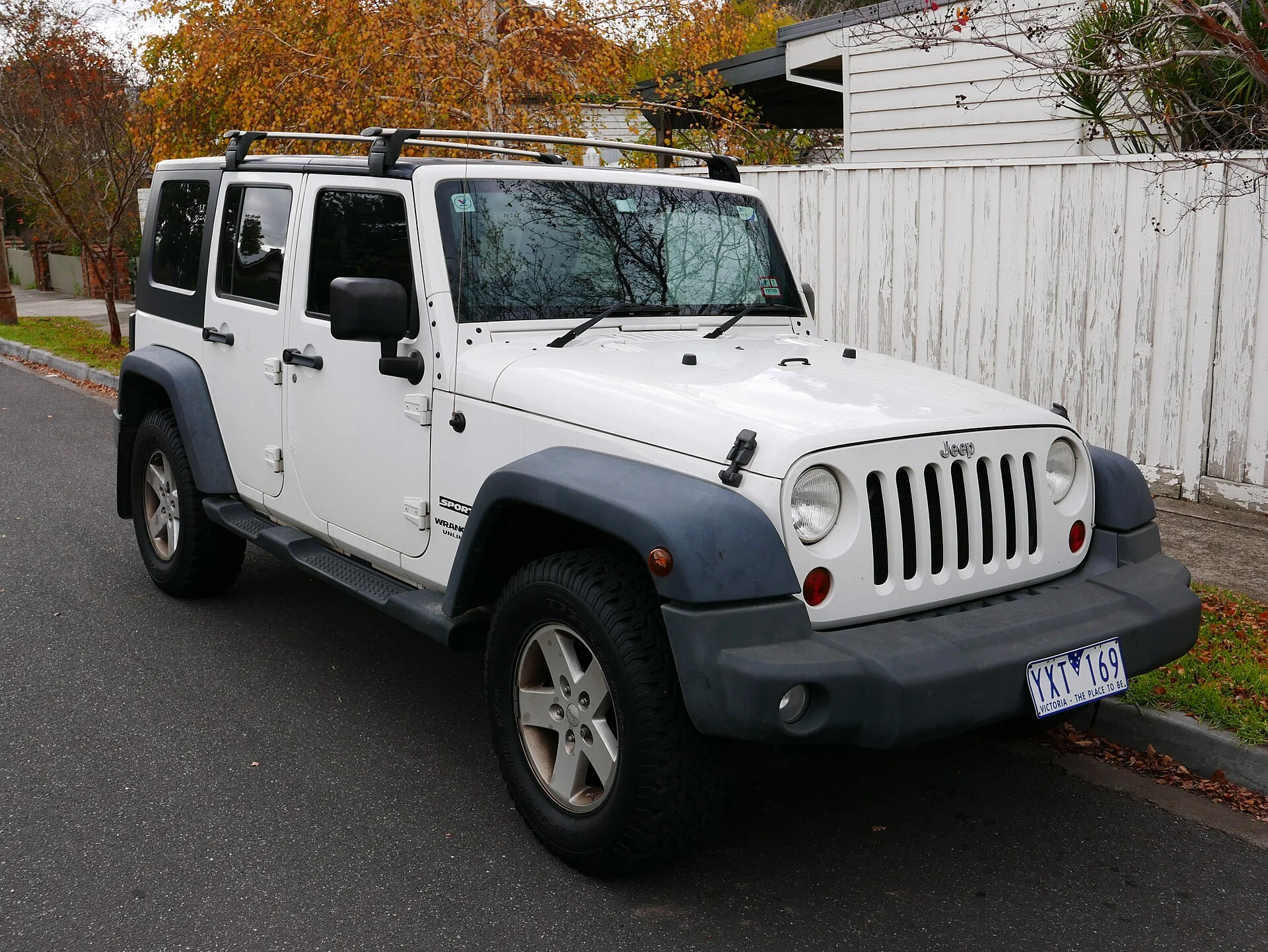 White four-door Jeep Wrangler Unlimited with hardtop, front three-quarter view
