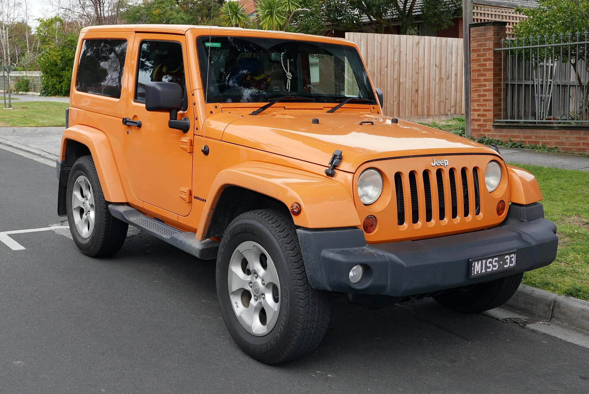 Orange two-door Jeep Wrangler with hardtop, front three-quarter view