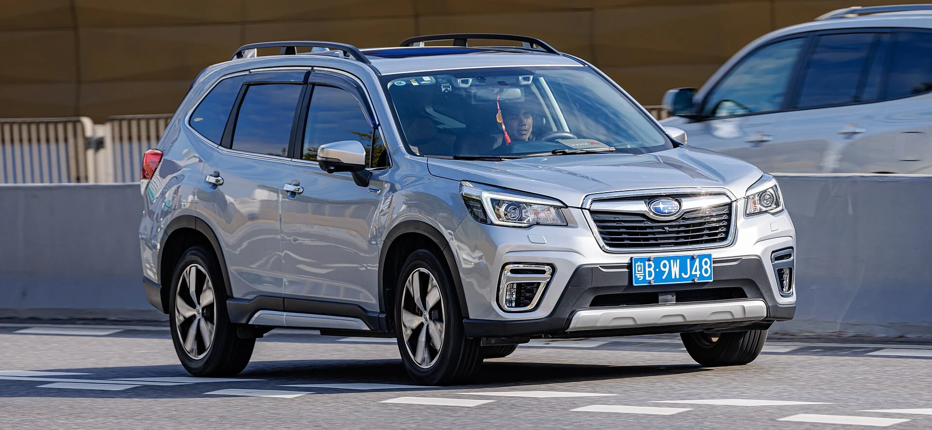 Silver Subaru Forester e-BOXER, fifth-generation SK, with raised roof rails, front three-quarter view on a road.