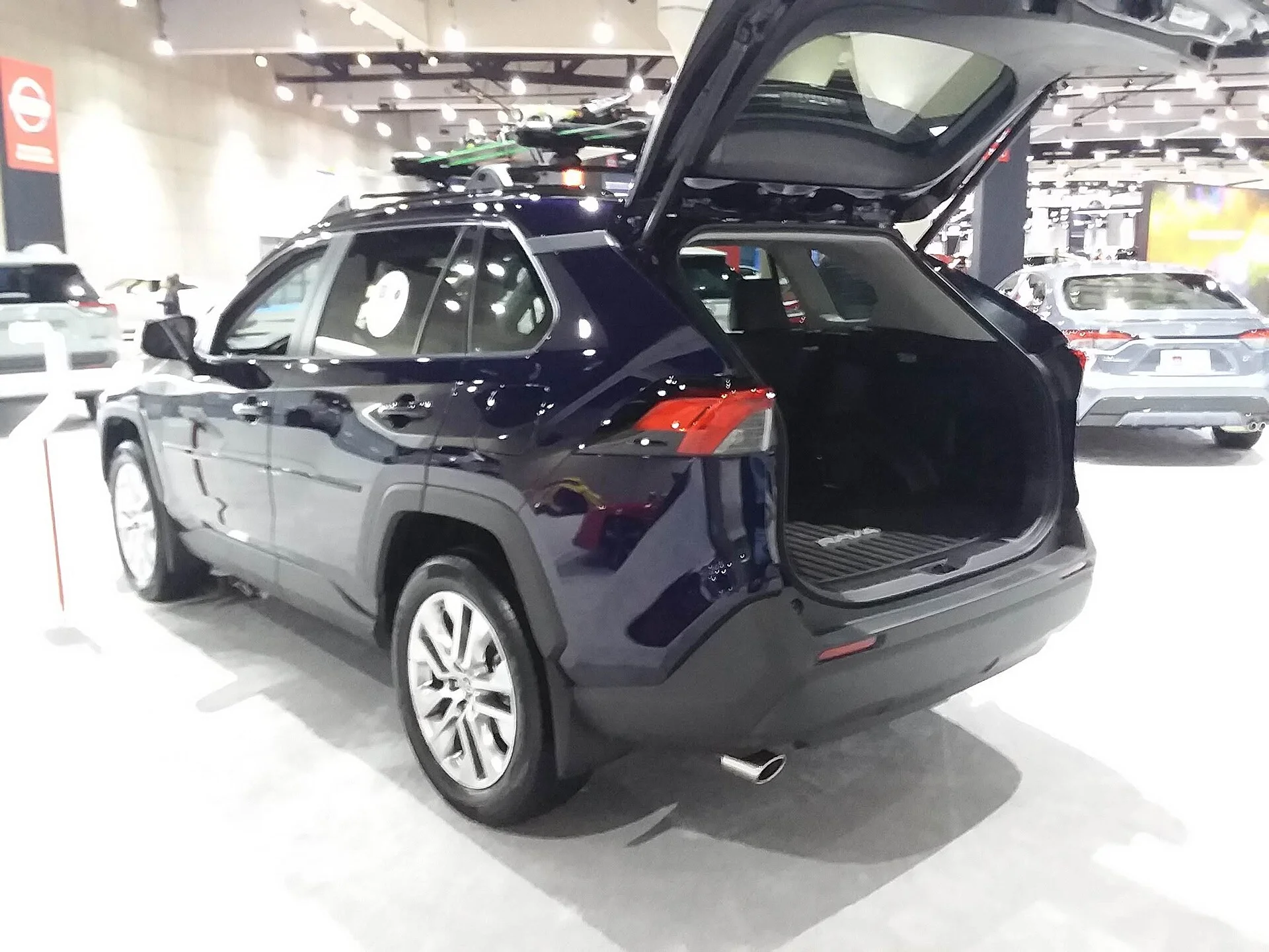 Dark-blue Toyota RAV4 with the rear liftgate open, showing the cargo area