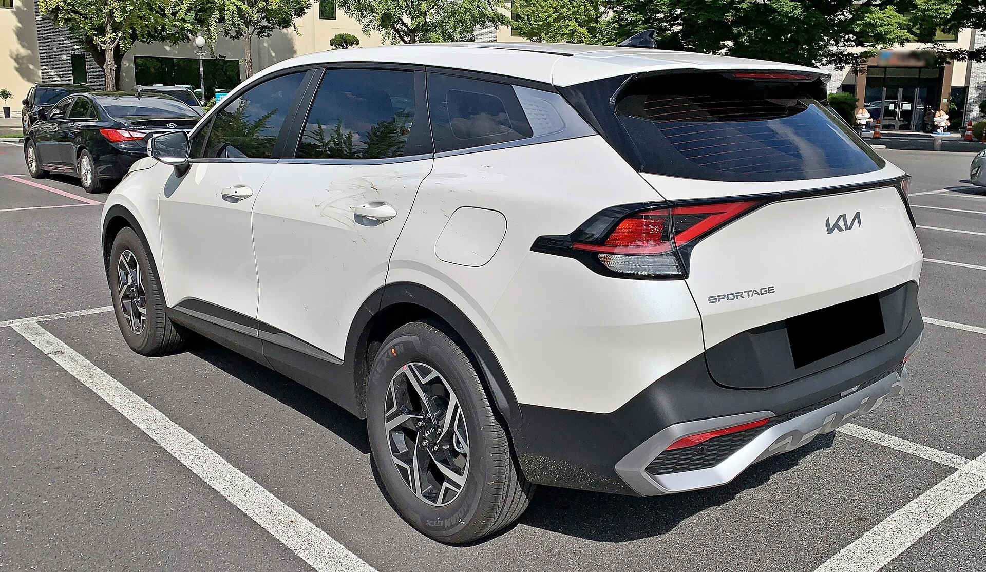 White Kia Sportage, current generation, rear three-quarter view
