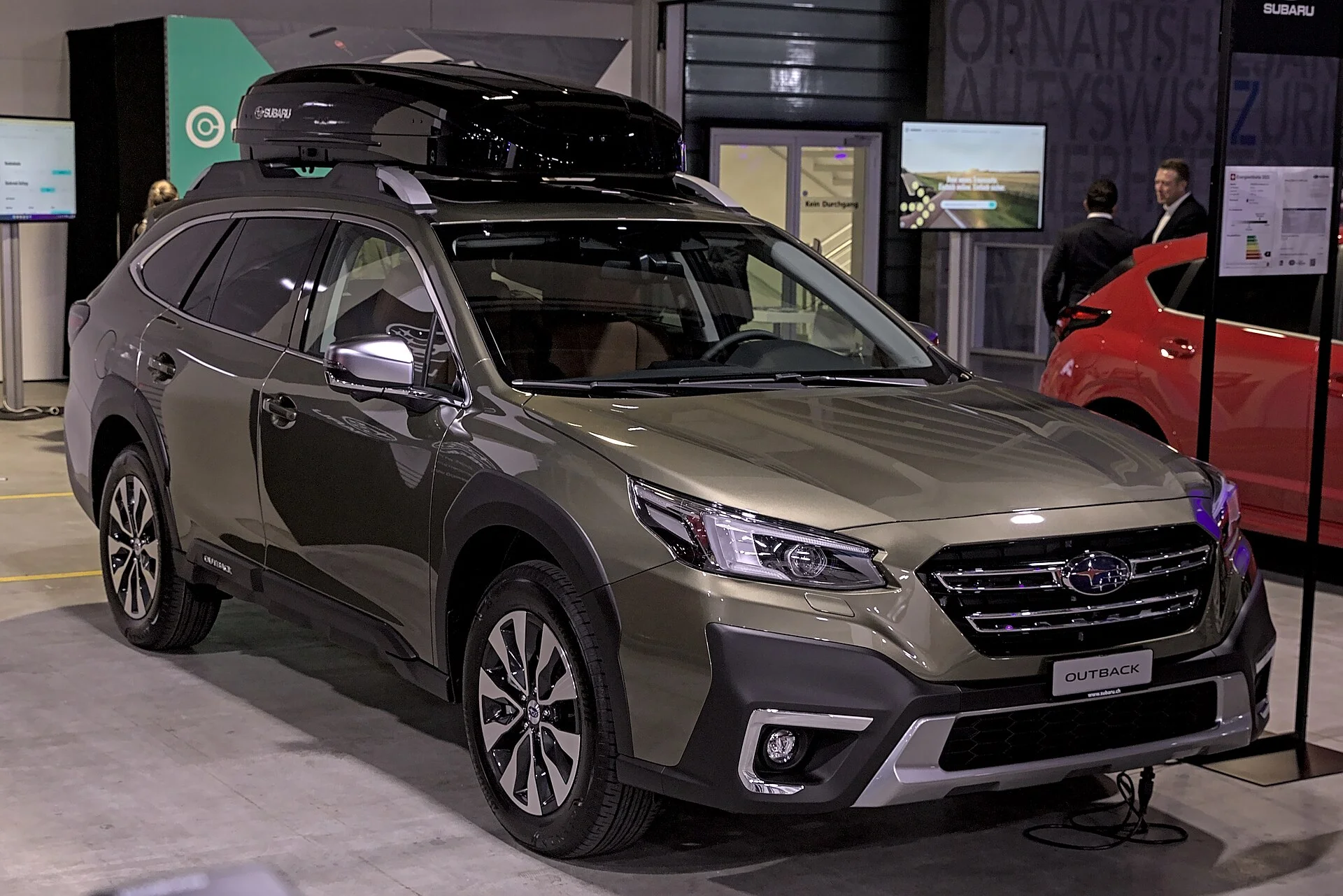 A tan Subaru Outback carrying a roof cargo box