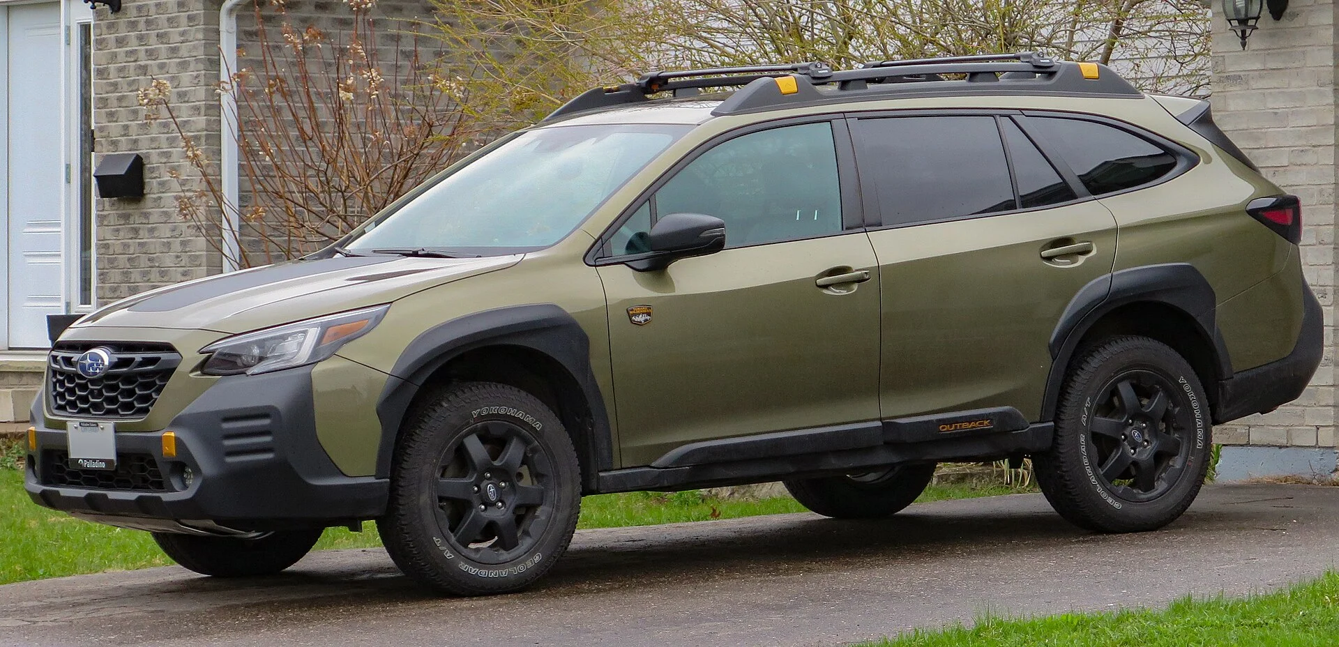 A green Subaru Outback Wilderness with roof rails for a rooftop tent
