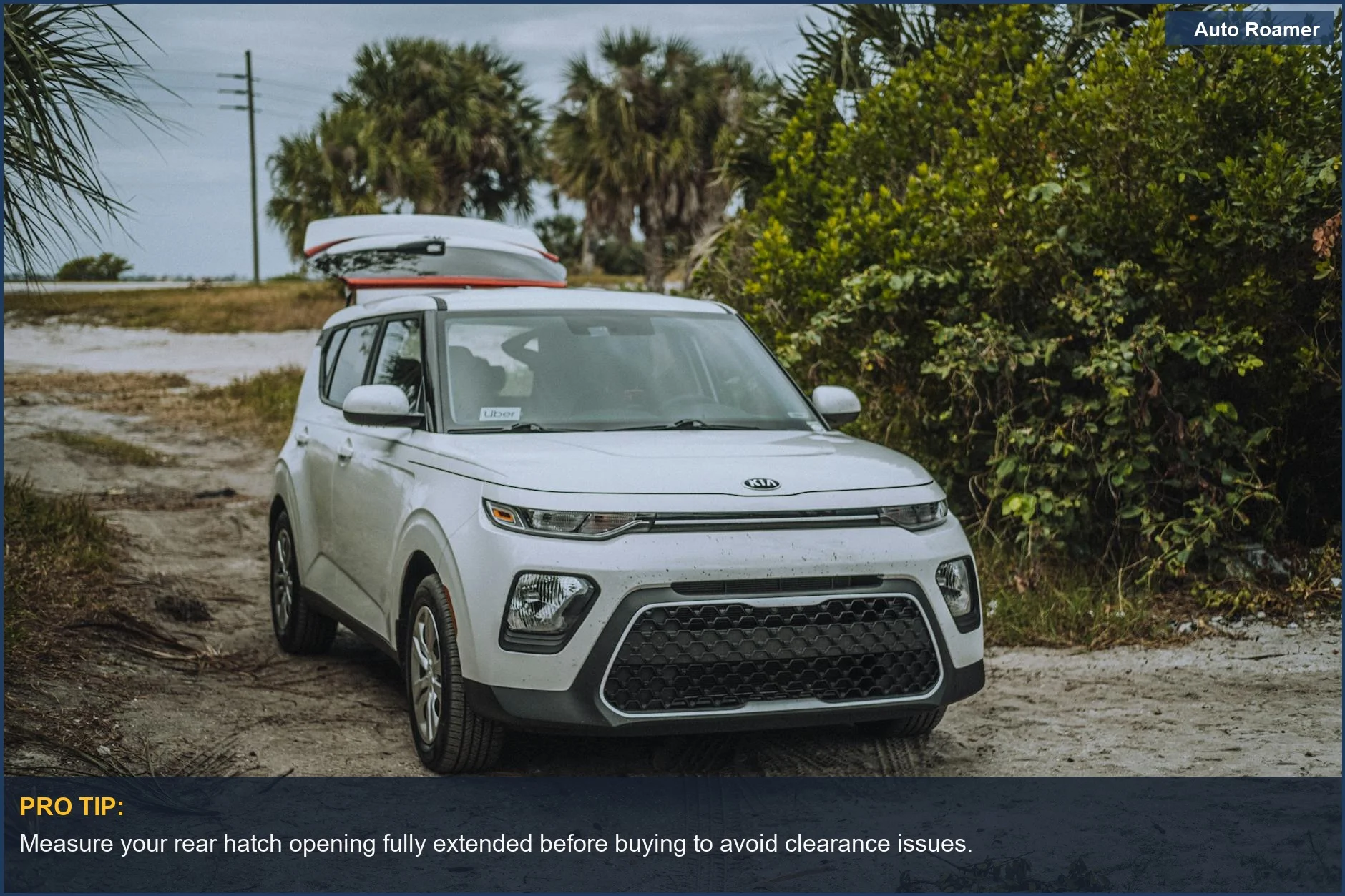 White SUV with a roof cargo box parked on a dirt road, ideal for outdoor trips.