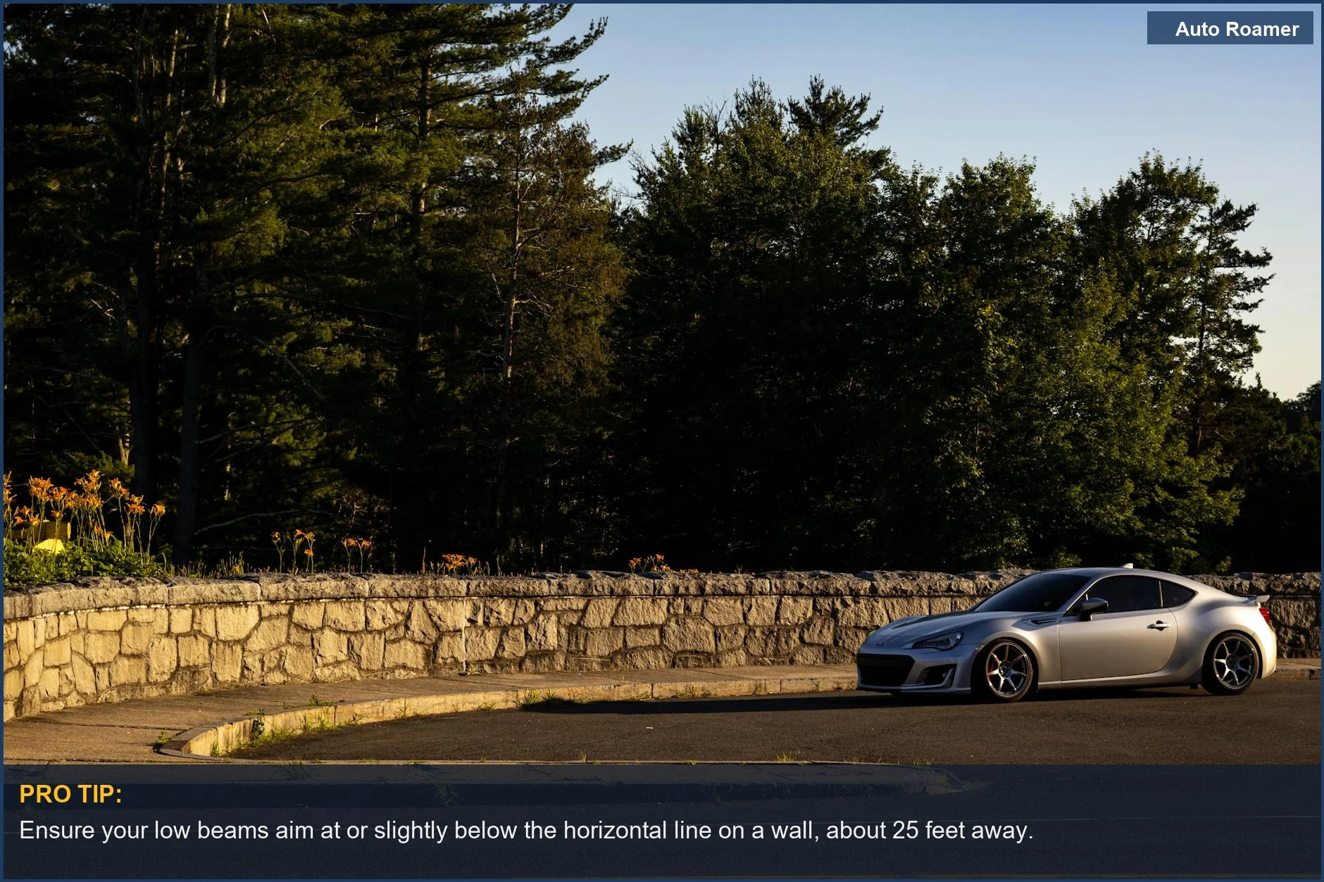 Un coche deportivo plateado aparcado junto a un muro de piedra entre árboles frondosos durante el día, simbolizando la preparación para la conducción nocturna.