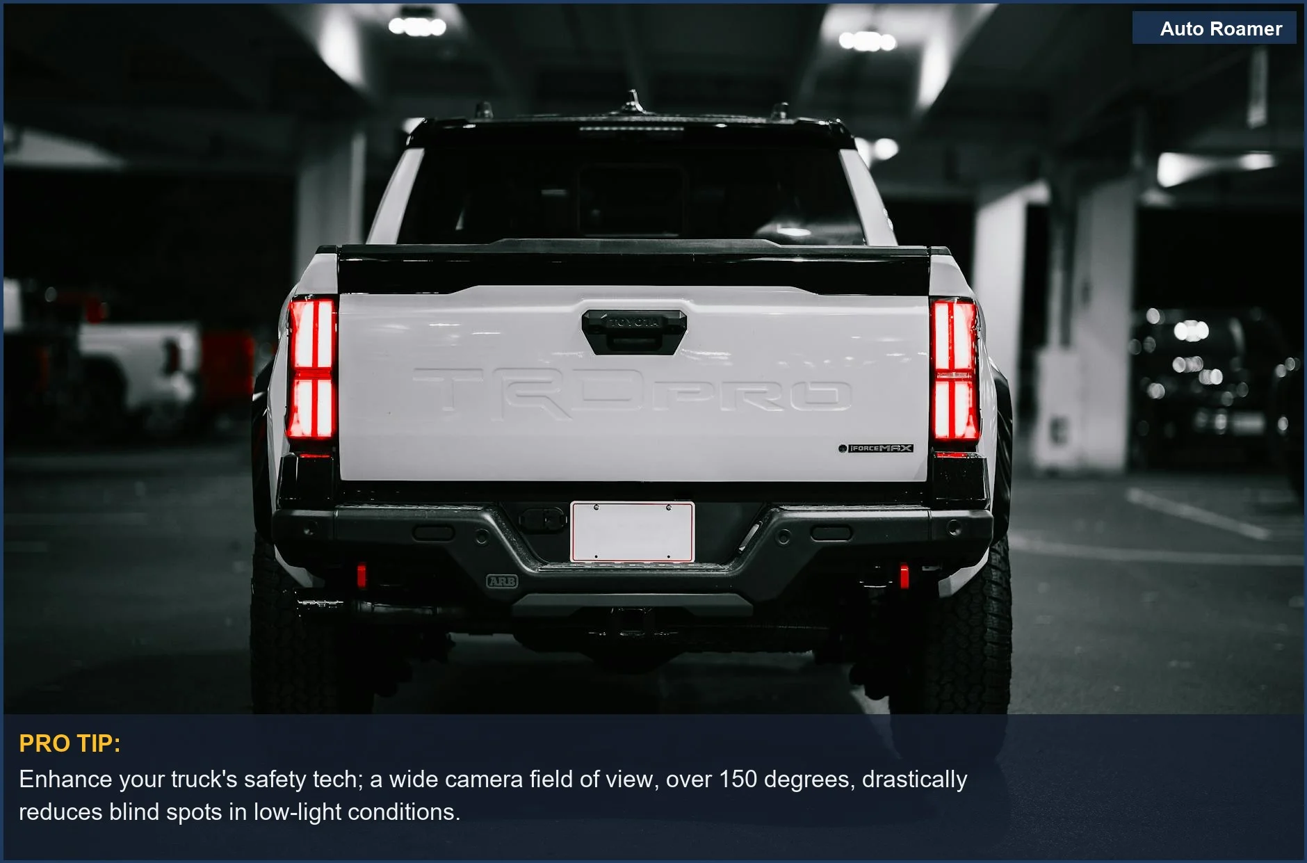 Rear view of a white pickup truck with illuminated tail lights in a dark parking garage.