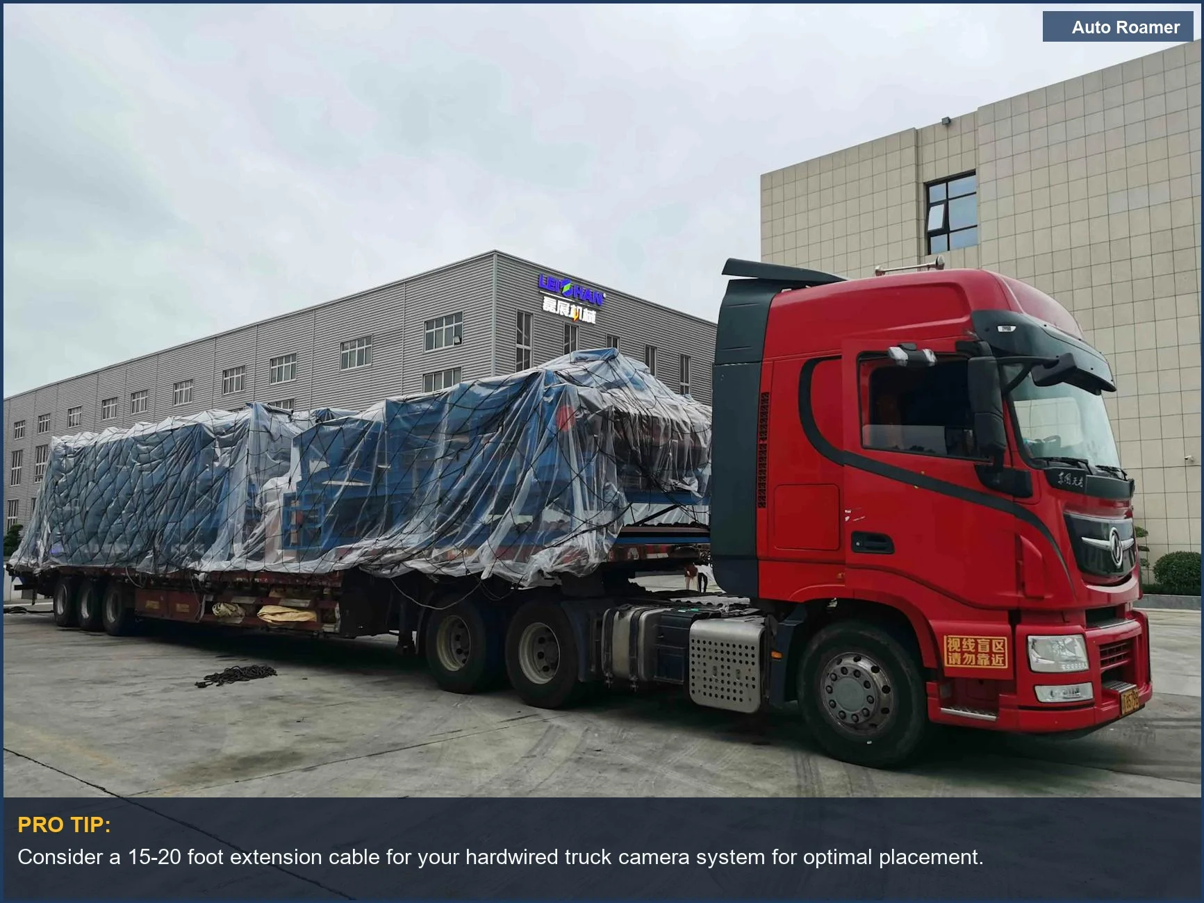 Red older truck with large cargo in industrial area, ideal for truck camera systems.