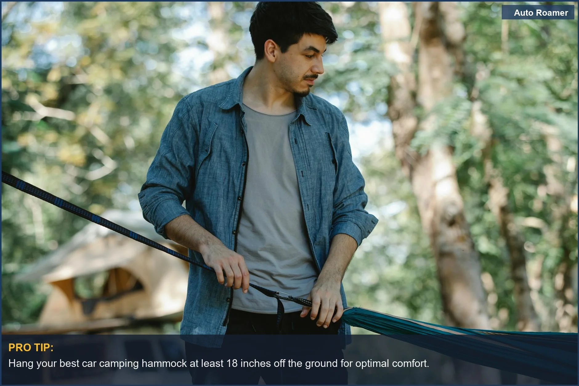 Bearded camper setting up a lightweight camping hammock between trees near a car.