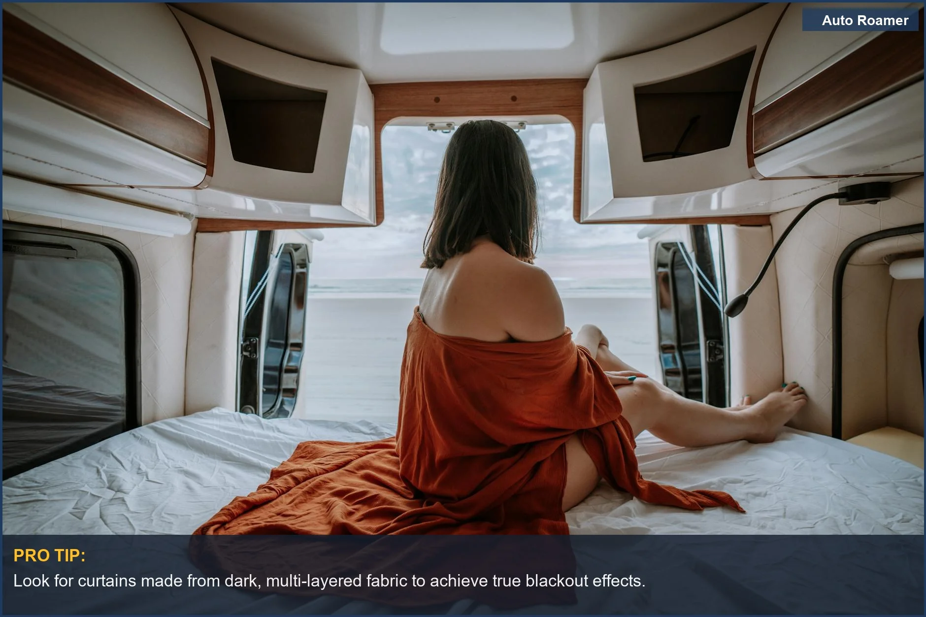 Woman enjoying ocean view inside van, wrapped in blanket, seeking personal space.