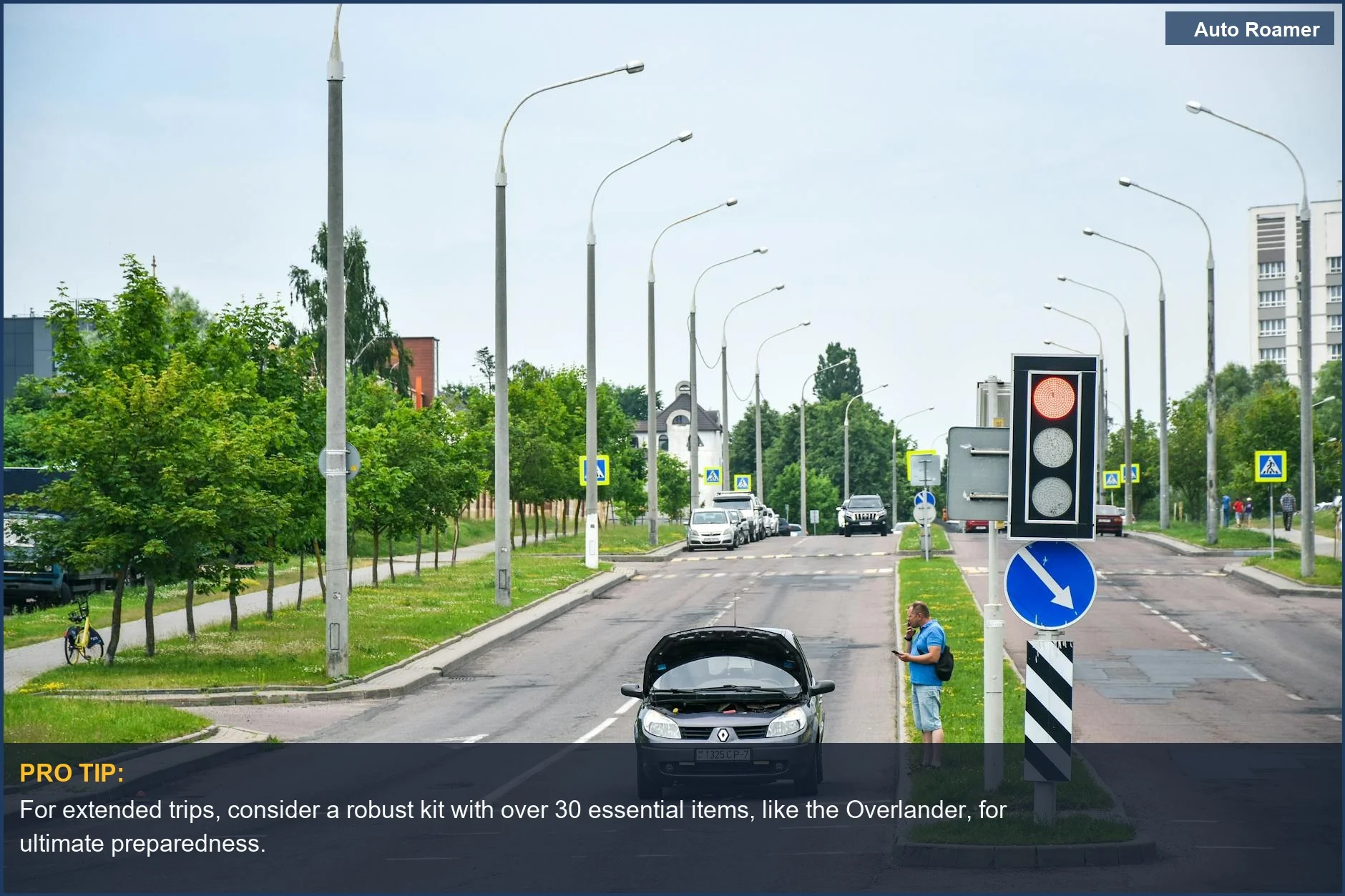 Man looking at phone beside a broken car on a city street, highlighting the need for roadside assistance tools in your car emergency kit.