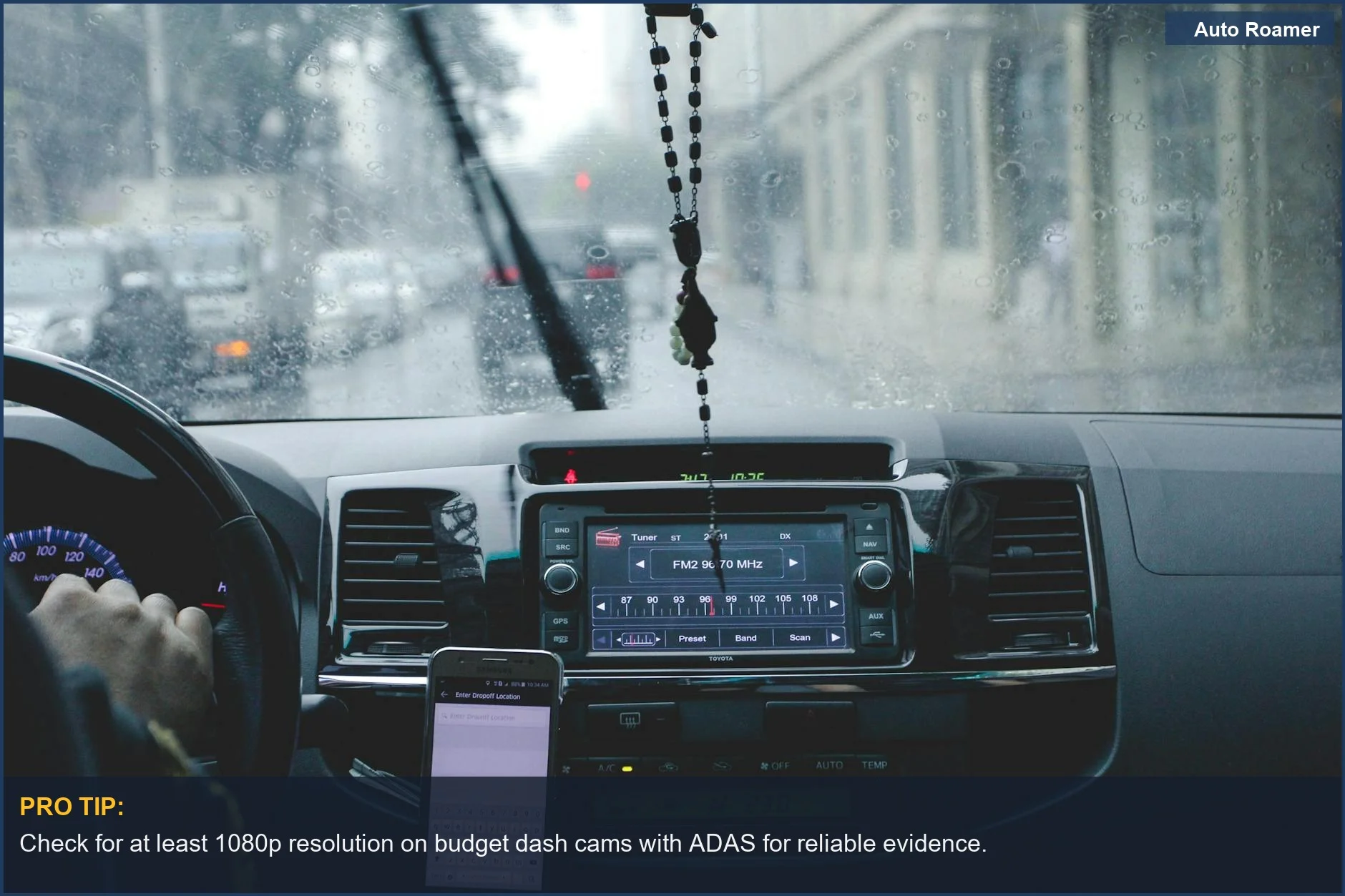 Driver navigating a rainy cityscape with a dashcam and phone, showing budget dashcams with ADAS capabilities.