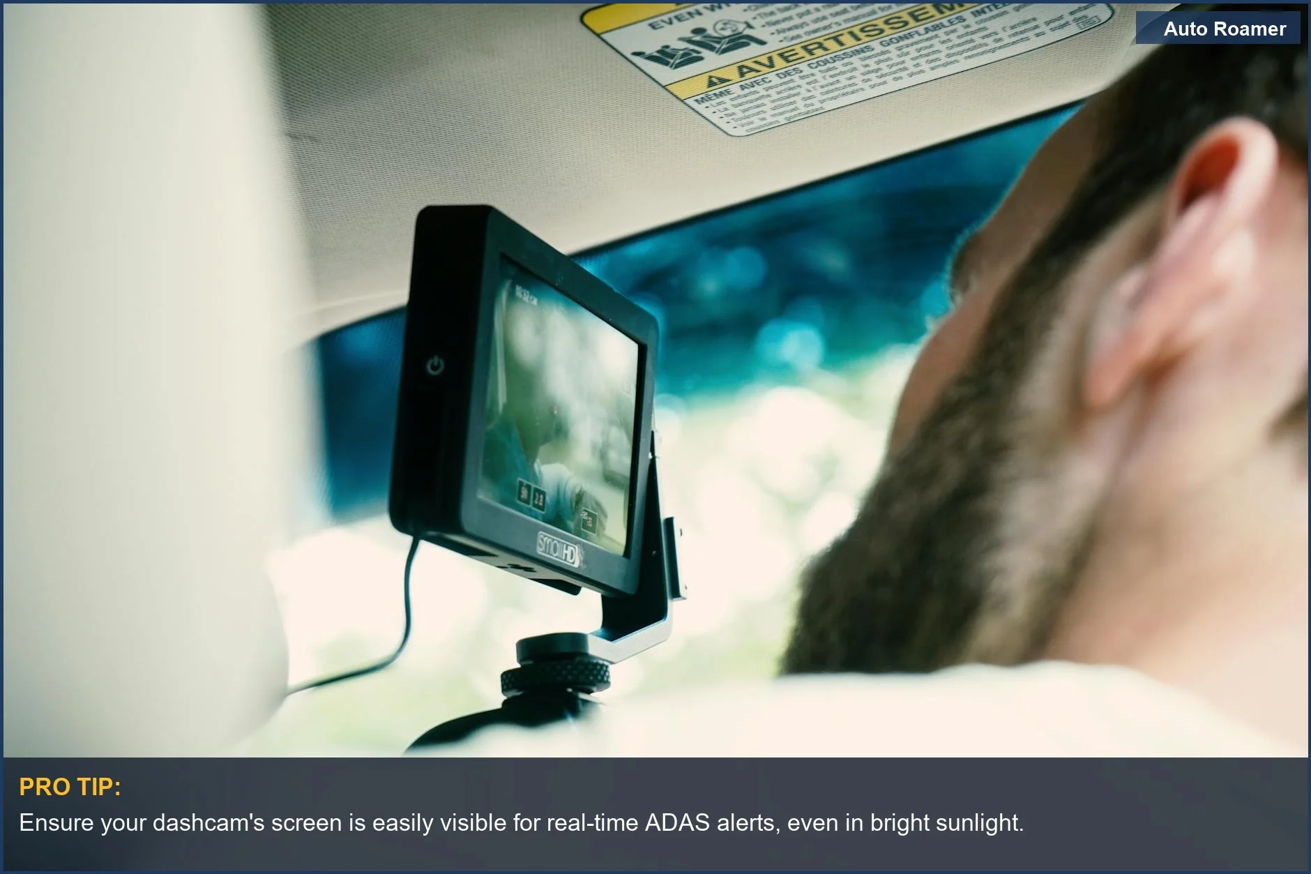Driver uses a modern dashcam with ADAS features, focusing on its clear display for advanced safety.