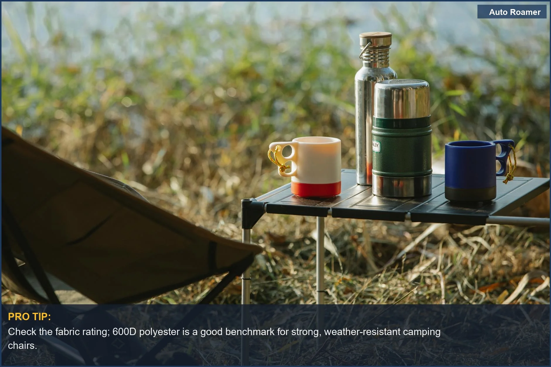 Close-up of a durable folding chair with hot drinks on a portable table by a grassy shore.
