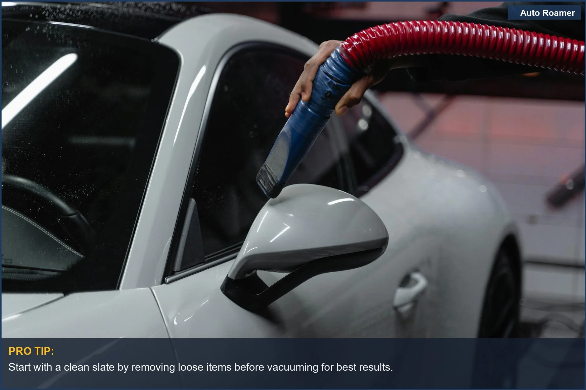 White sports car being vacuumed indoors, showcasing meticulous maintenance.