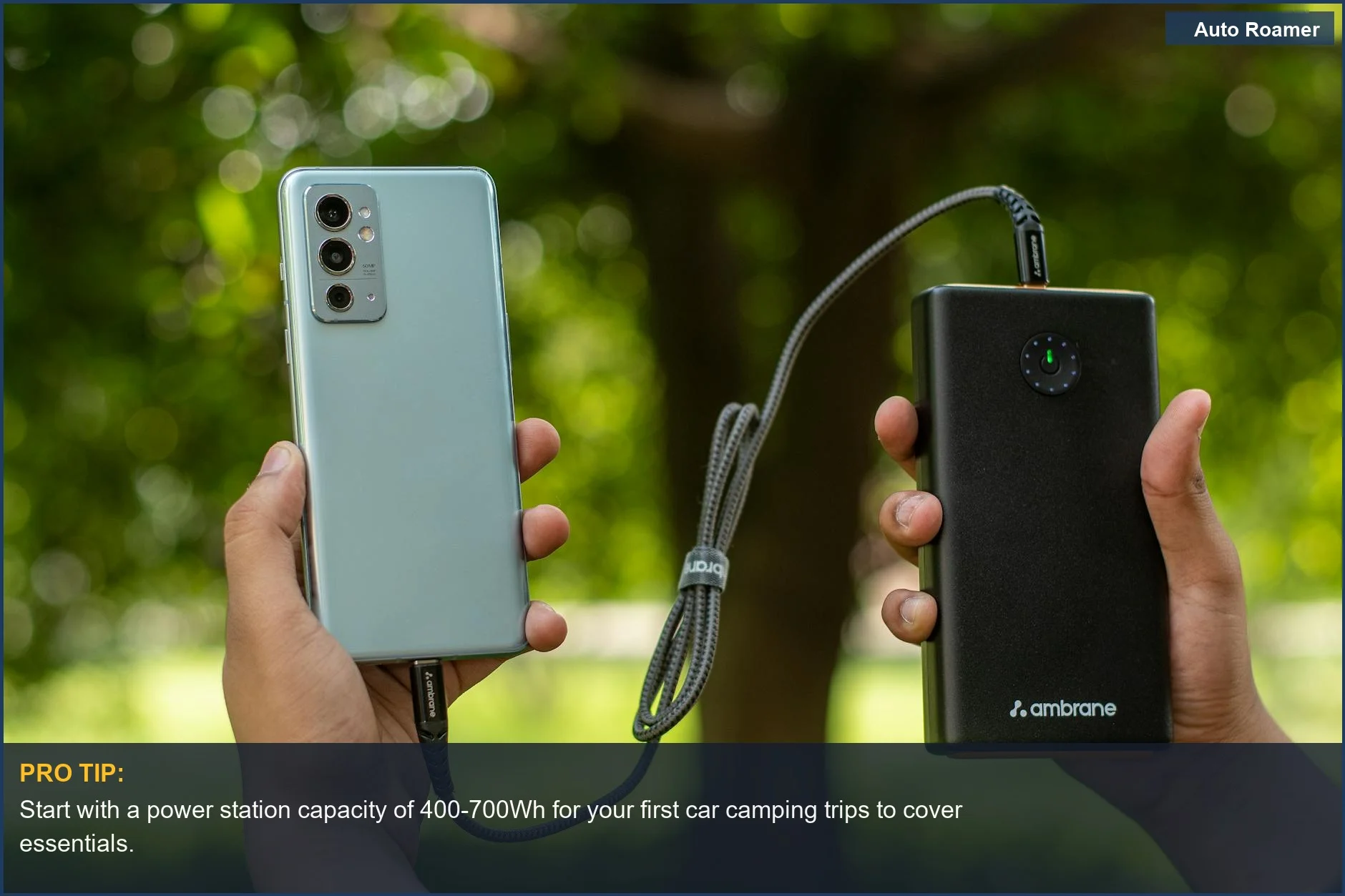 Close-up of hands holding a smartphone connected to a portable power bank for camping.