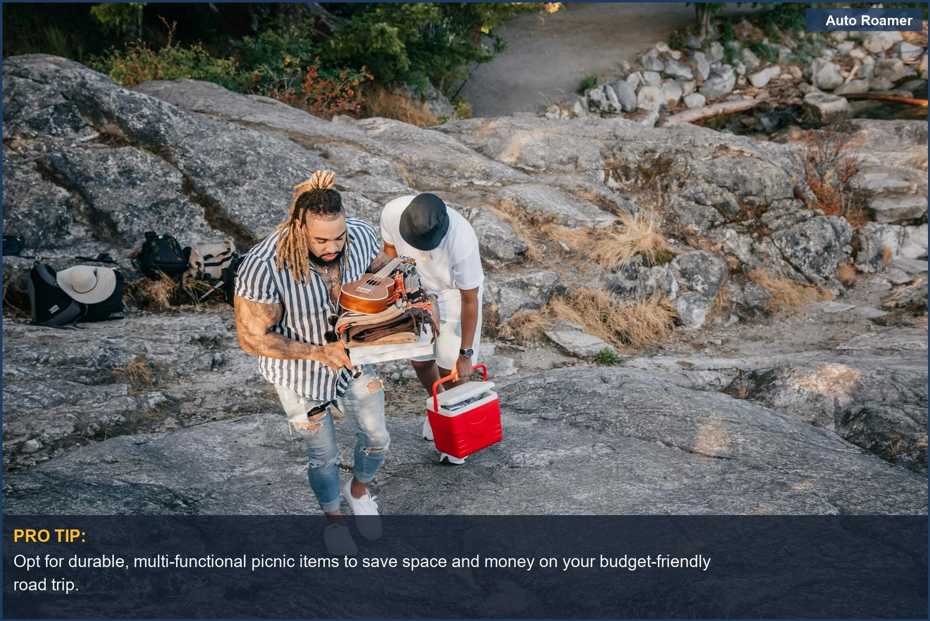 Hikers carry picnic supplies up a rocky trail, showcasing budget-friendly road trip essentials for outdoor adventures.