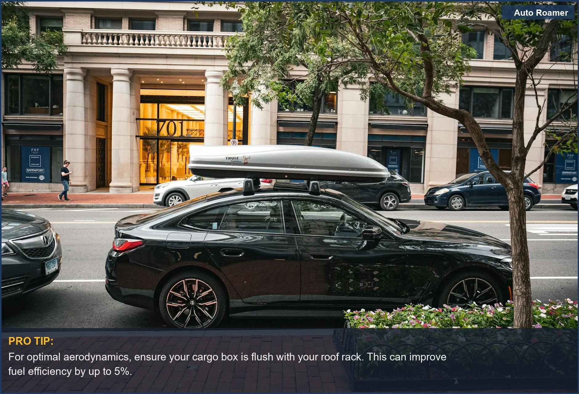 Sleek black sedan parked on a city street, featuring a rooftop cargo box for enhanced travel capacity.
