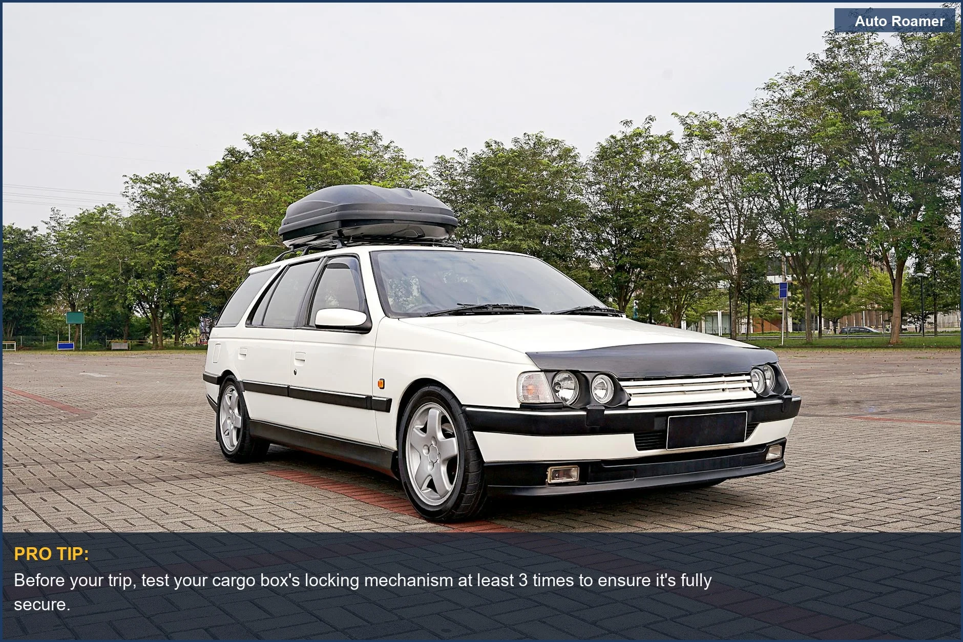 Classic white station wagon equipped with a rooftop cargo box, ready for travel in an urban setting.